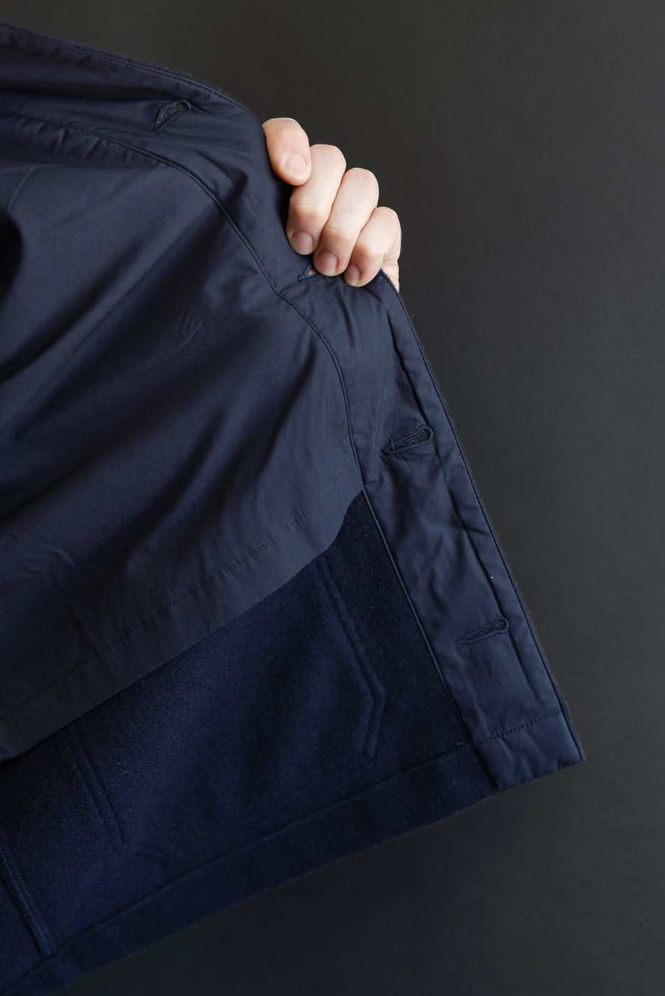 Close-up view of the interior lining and hem of a navy blue jacket.