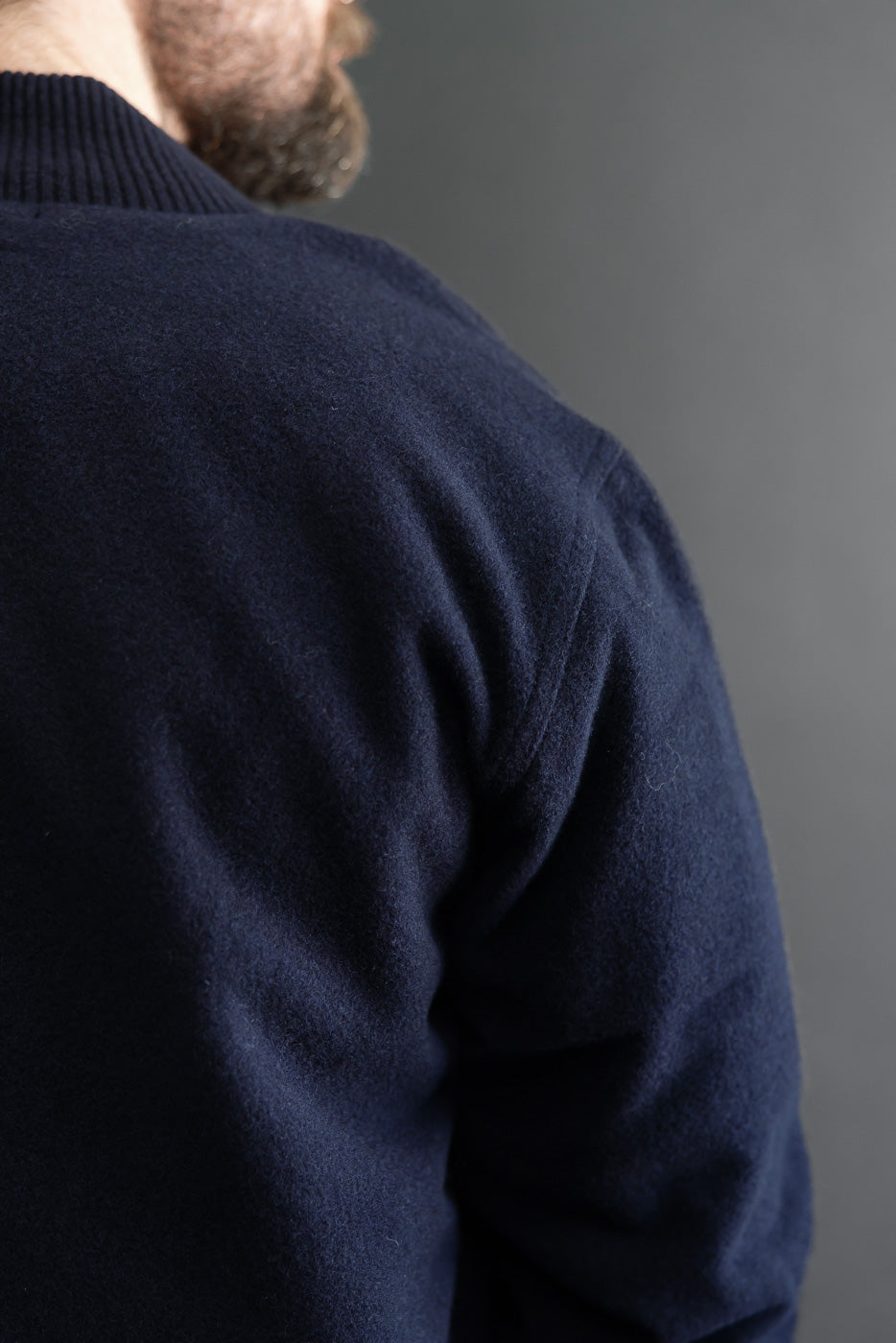 Close-up shot of the back and right shoulder of a navy blue textured knit sweater.