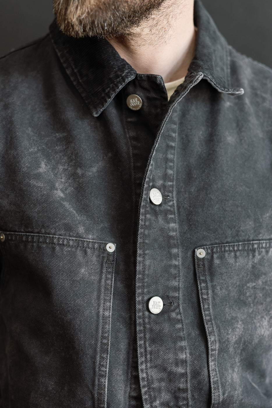 Close-up front view of a black canvas jacket on a male model, 5'9