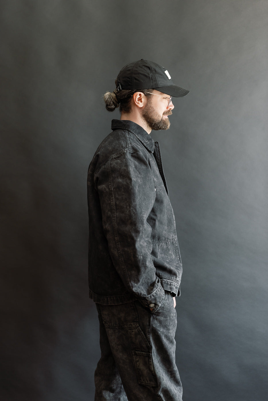 Side view of male model, 5'9, 165lbs, athletic build, wearing asphalt canvas jacket and pants, full-body