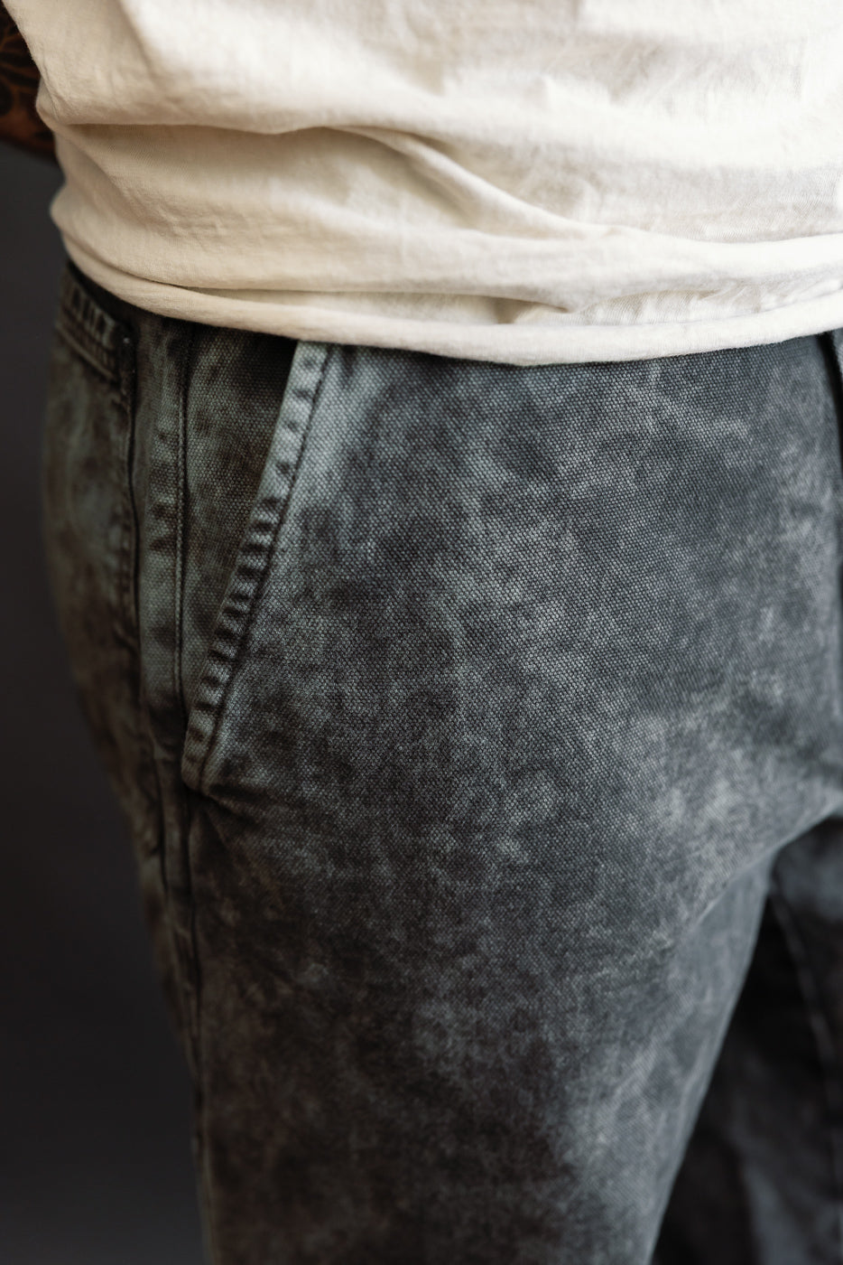 Close-up of front left hip and pocket on men's asphalt canvas chino pants, worn by male model, 5'9