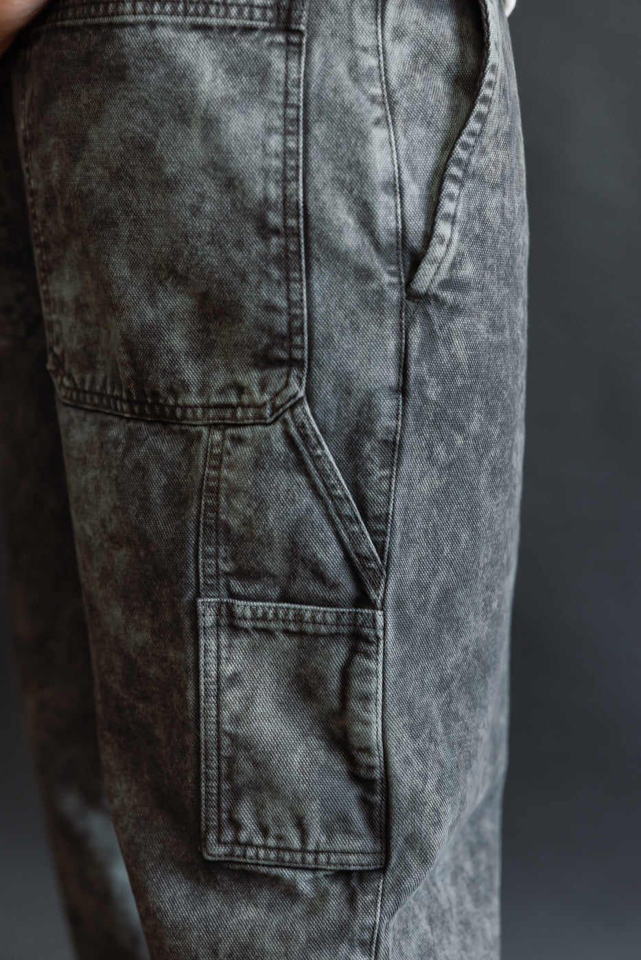 Close-up of men's asphalt canvas chino pants, right side pocket detail, on 5'9