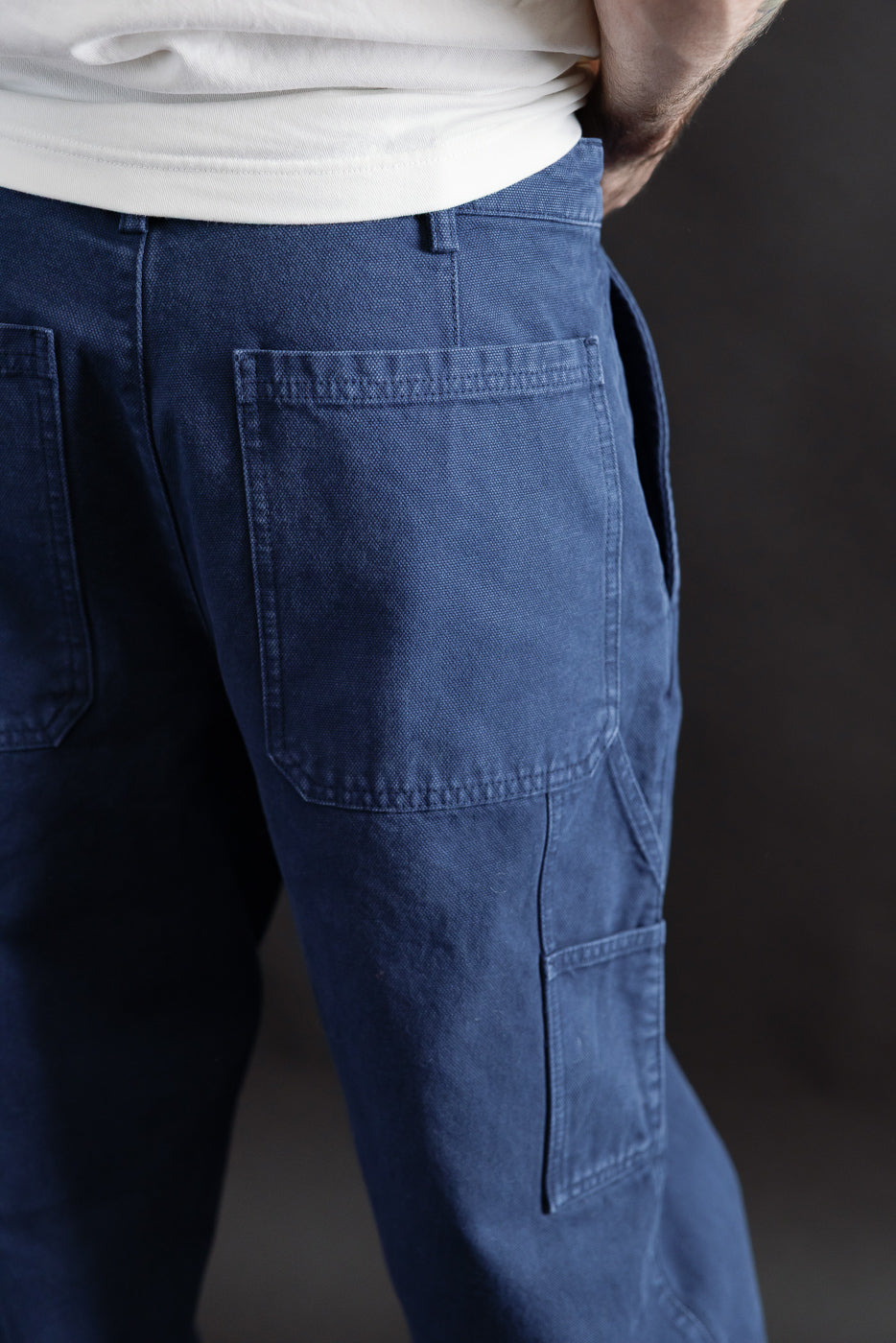 Close-up rear view of men's indigo blue canvas chino back pockets on male model, 5'9