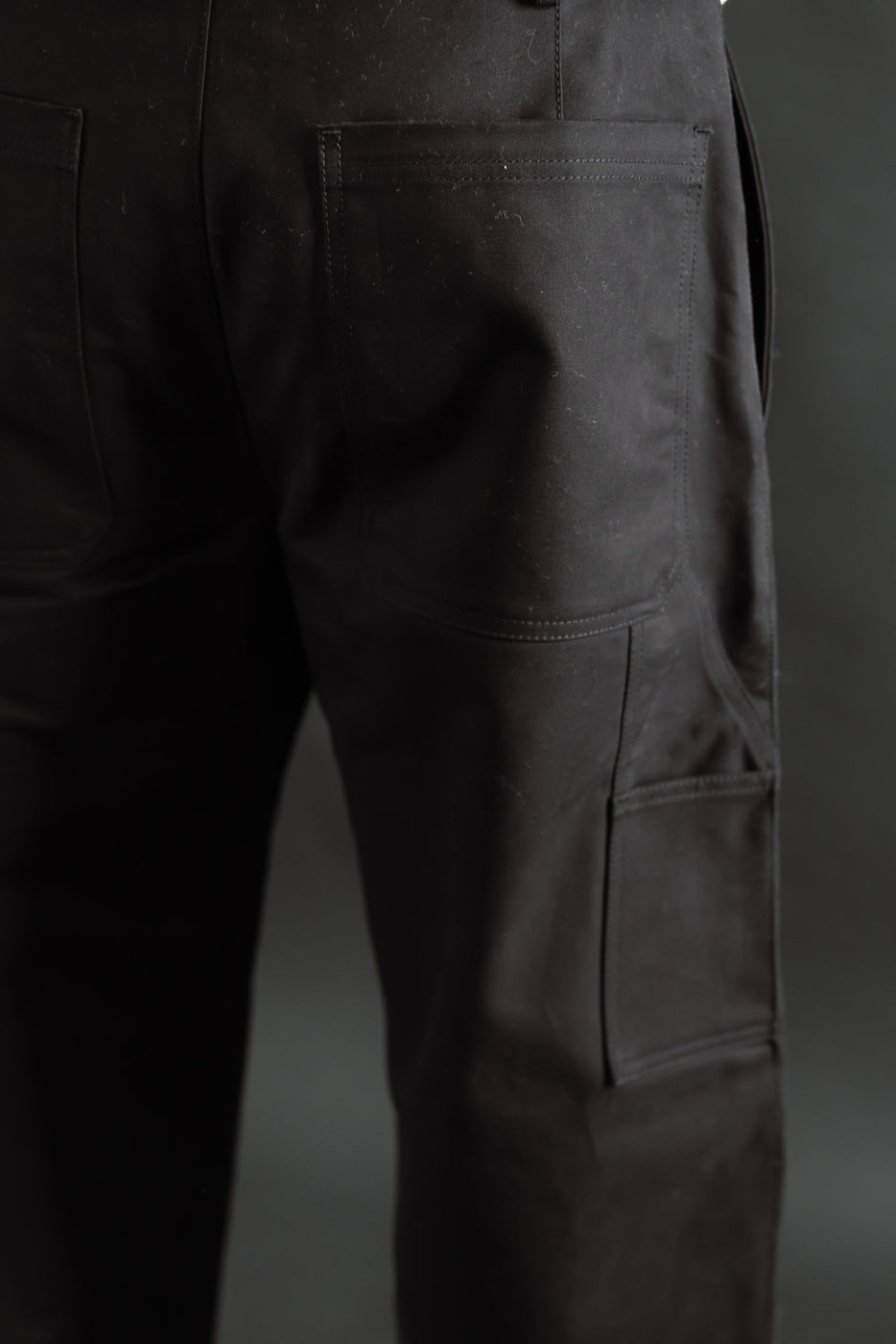 Close-up of men's black cotton Oakland Chino, rear and side pocket detail, athletic build
