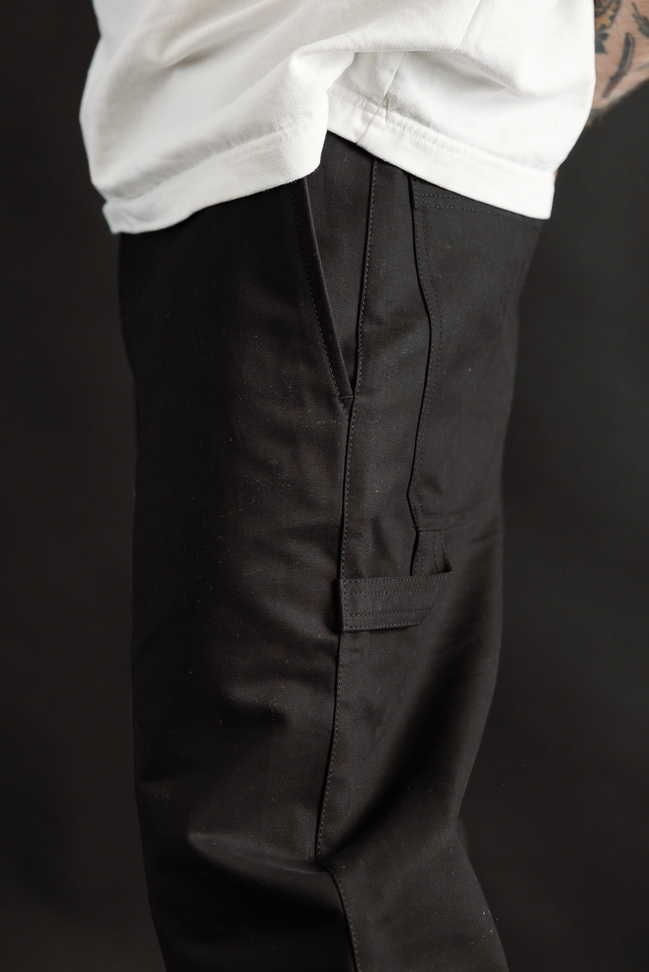 Close-up side view of men's black Oakland chino pants, pocket details, on 5'9