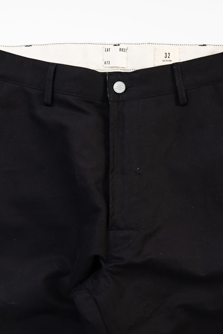 Close-up front view of Eat Dust Oakland Chino in black cotton, button and waistband detail.
