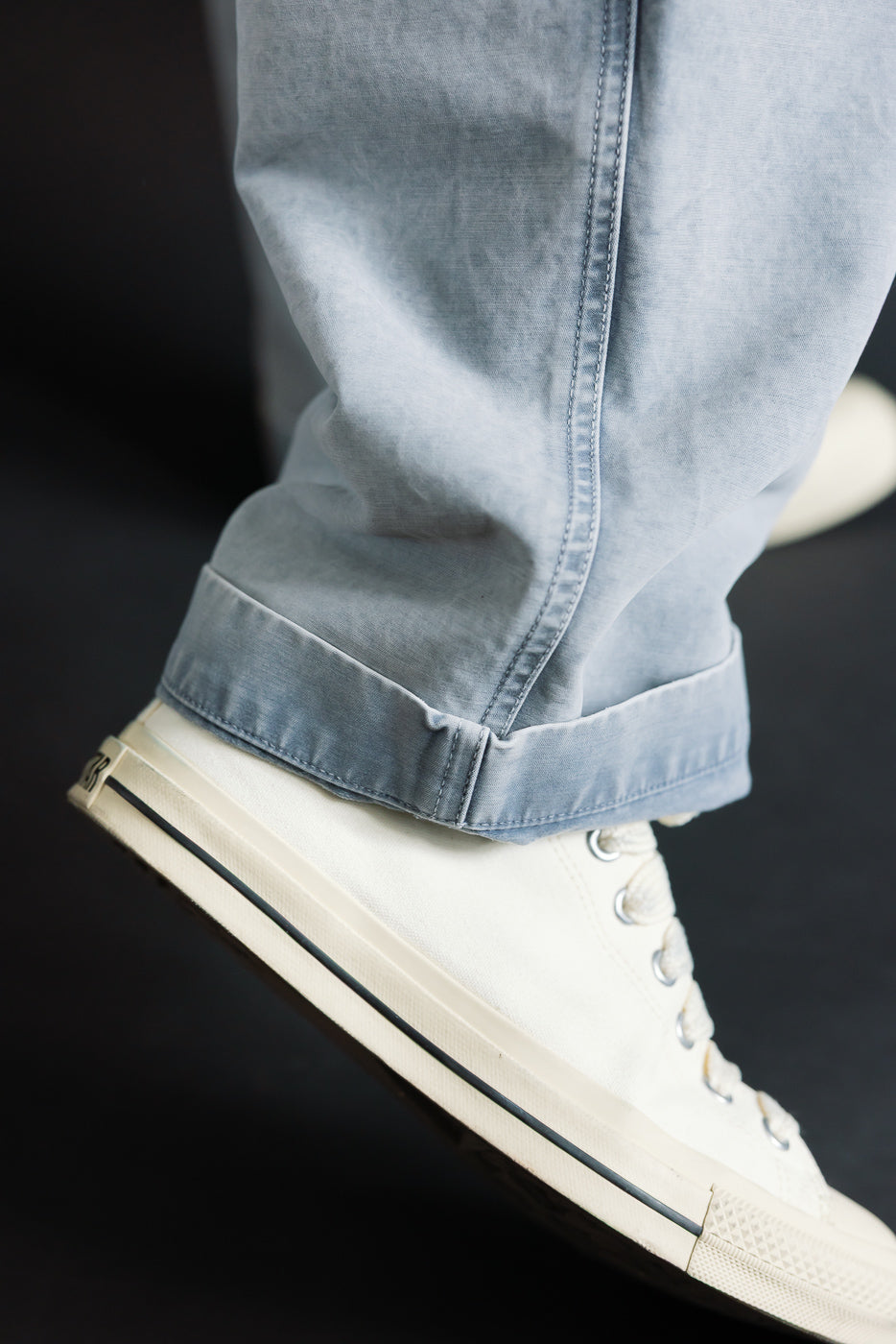 Close-up of coastal blue cotton chino pant leg cuff and sneaker, right lower leg, on 5'9