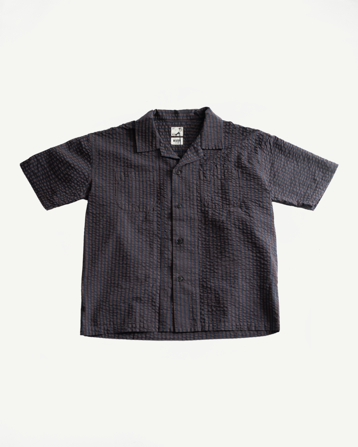 Flat lay front view of men's short sleeve seersucker denim aloha shirt, coffee navy, showing collar, buttons, chest pockets, and textured fabric.