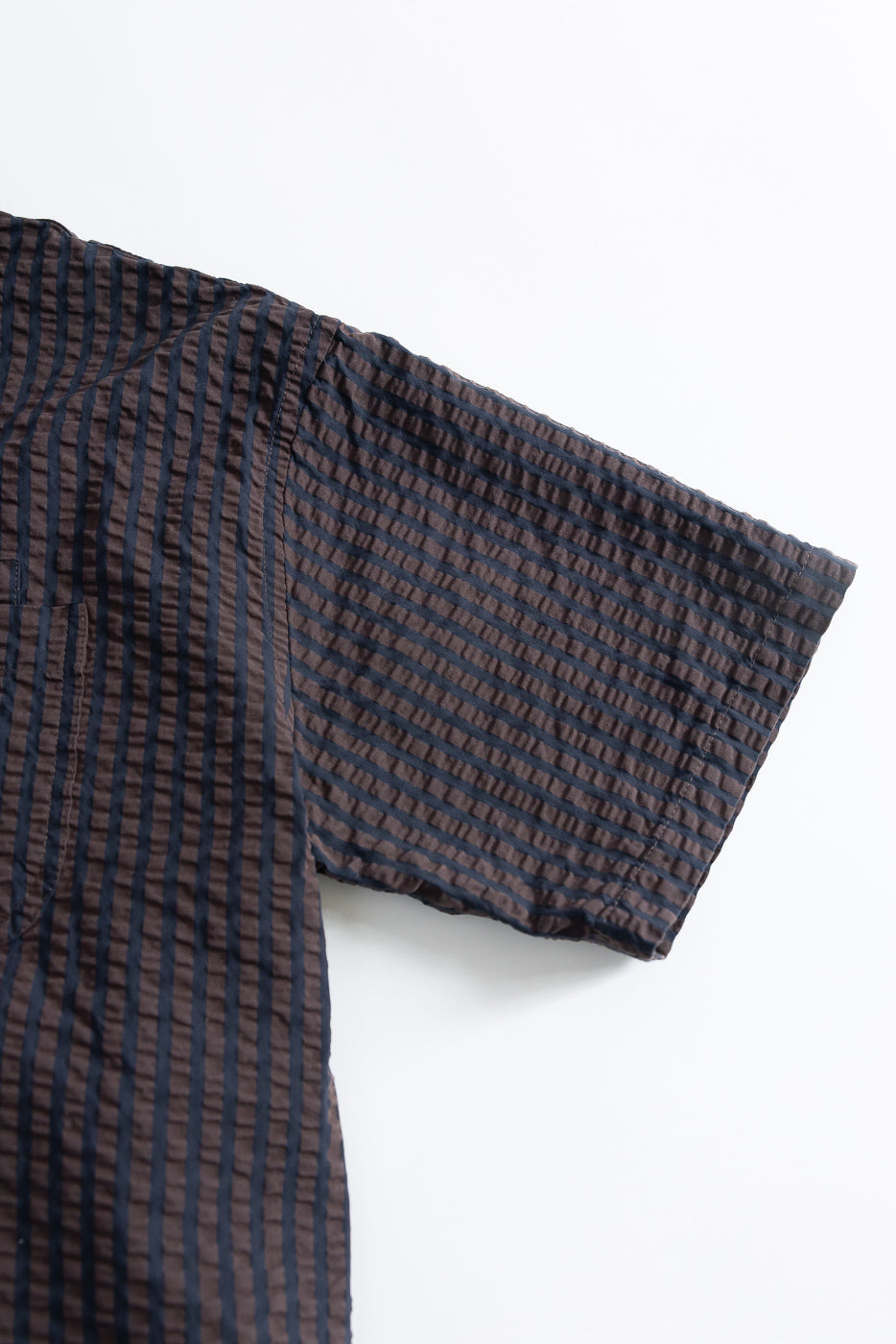 Close-up of right sleeve and upper front, seersucker denim shirt, brown and navy vertical stripes.