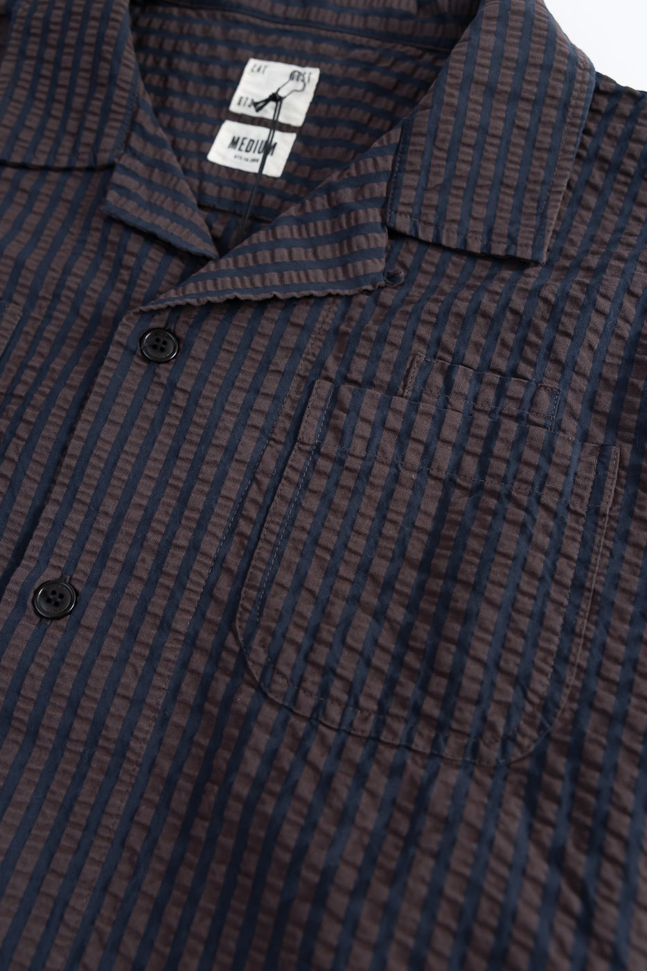 Close-up of front chest area on striped seersucker denim aloha shirt showing buttons, collar and pocket.
