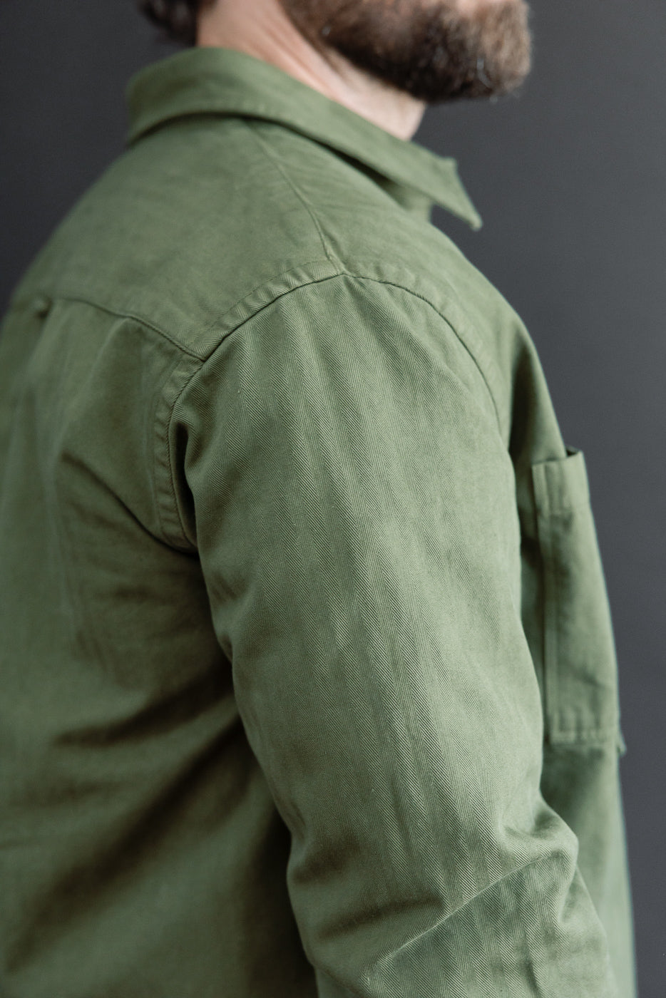 Close-up of the back and sleeve of an olive green shirt on a 5'9