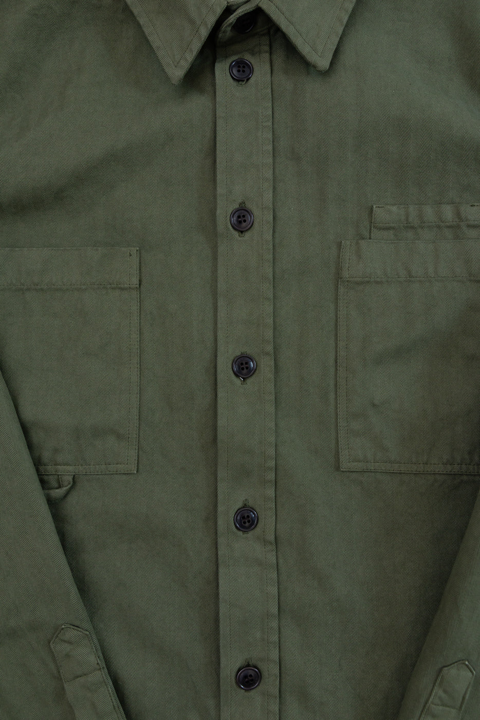 Close-up of the front of an olive green shirt showing the collar, buttons, and chest pockets.
