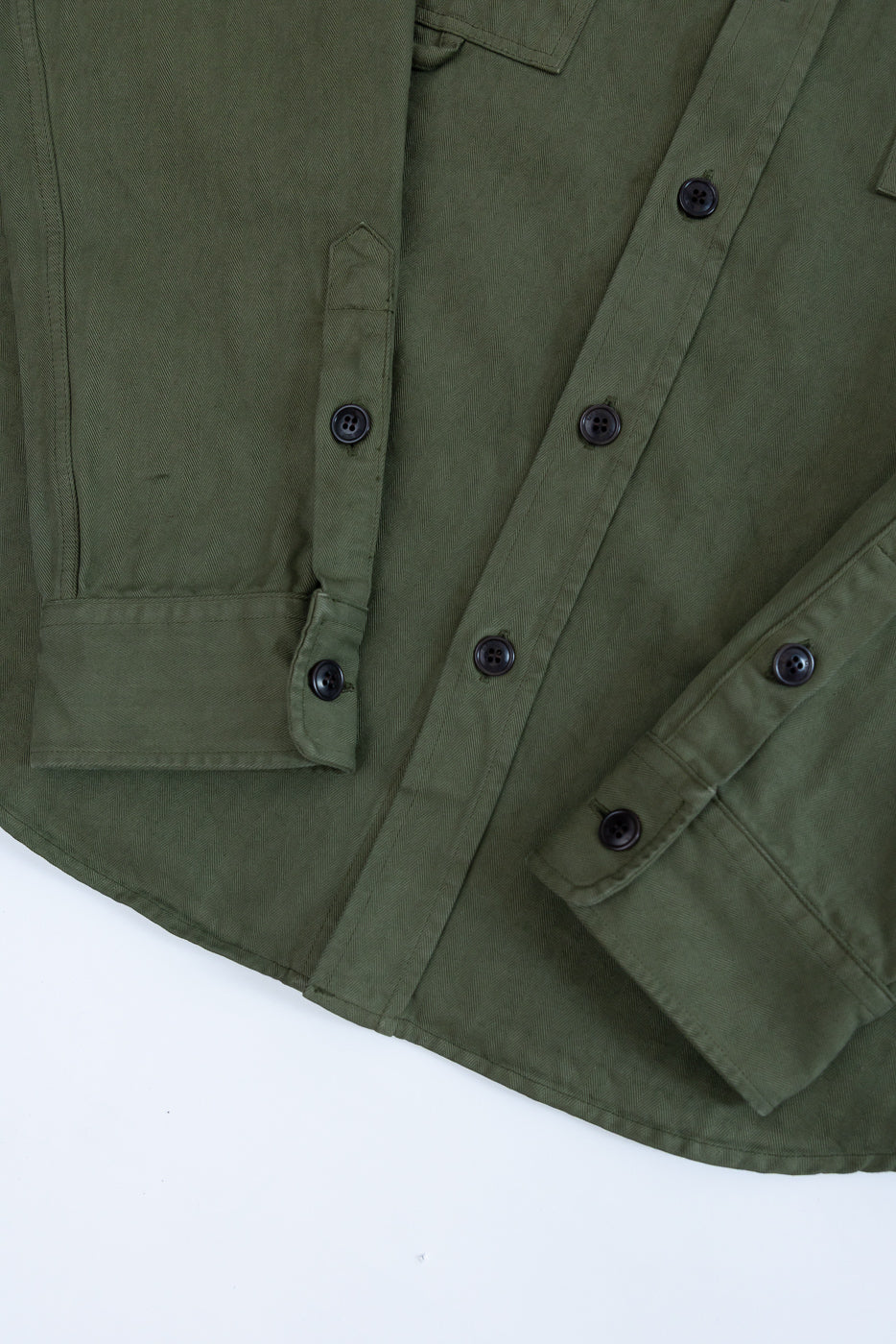 Close-up of the front of an olive green shirt showing button details and fabric texture.