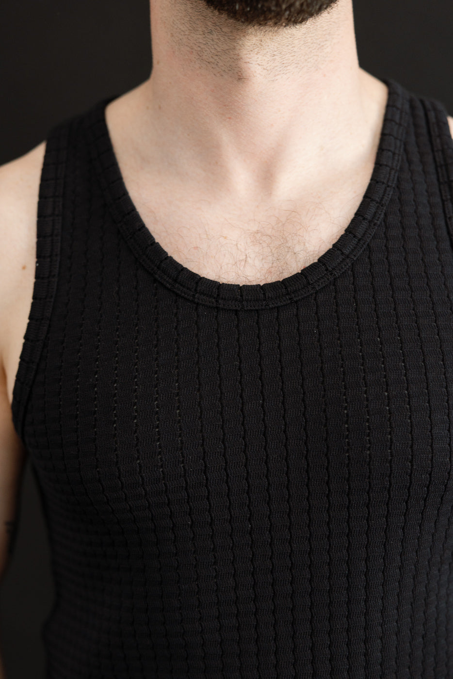 Close-up of front chest area of black mesh cotton tank top on male model, 5'9