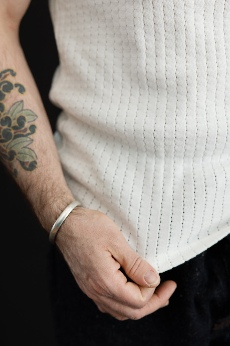 Close-up of male model's front midsection wearing white mesh cotton tank top, athletic build, fabric texture visible