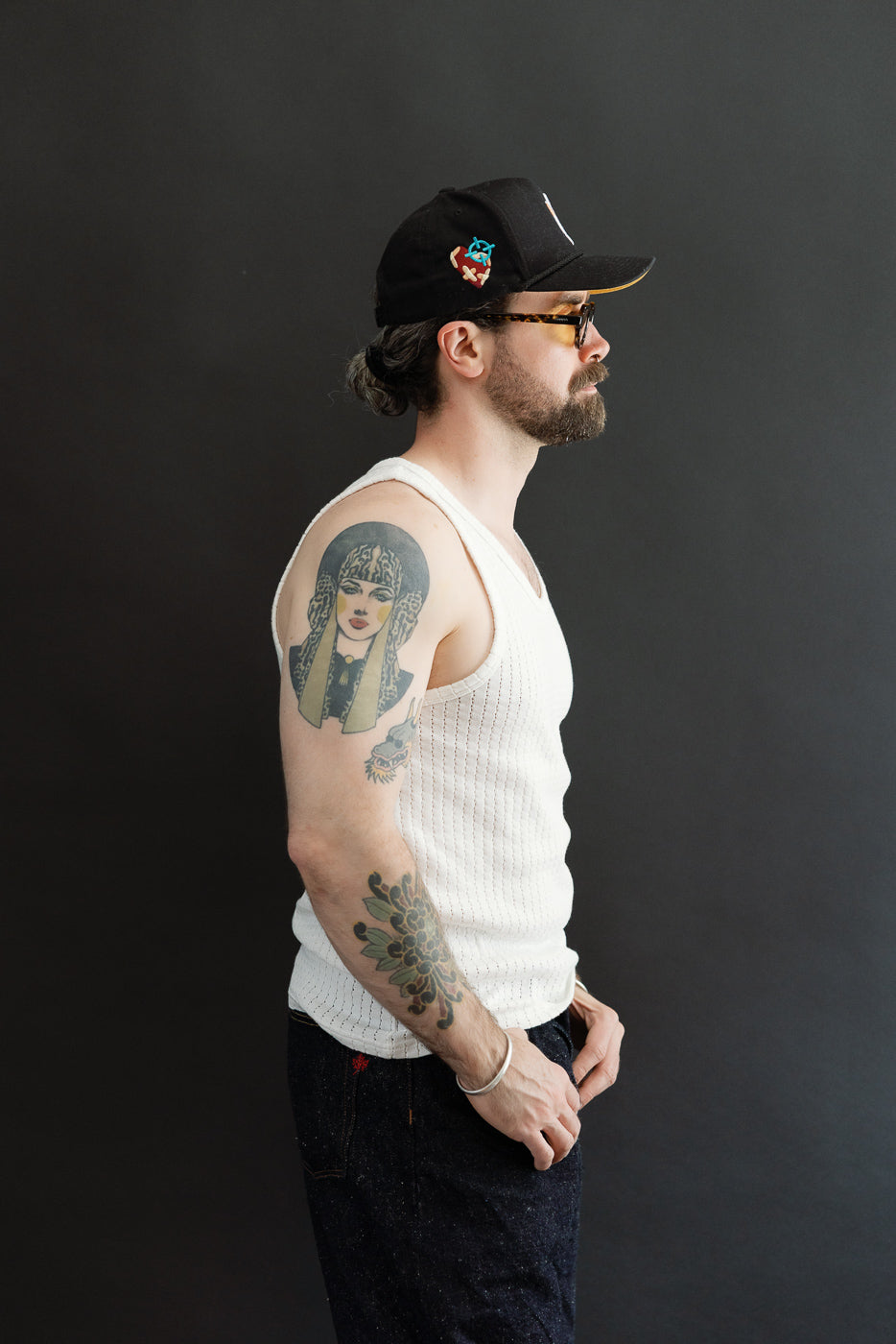 Male model 5'9, 165lbs athletic build wearing white mesh cotton tank top, left side view, full body