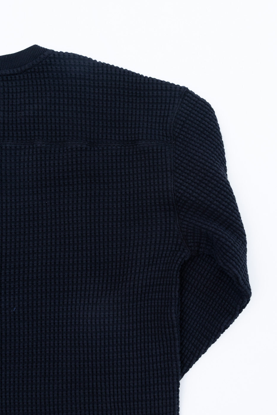 Close-up of the back of a navy blue waffle knit thermal shirt showing fabric texture.