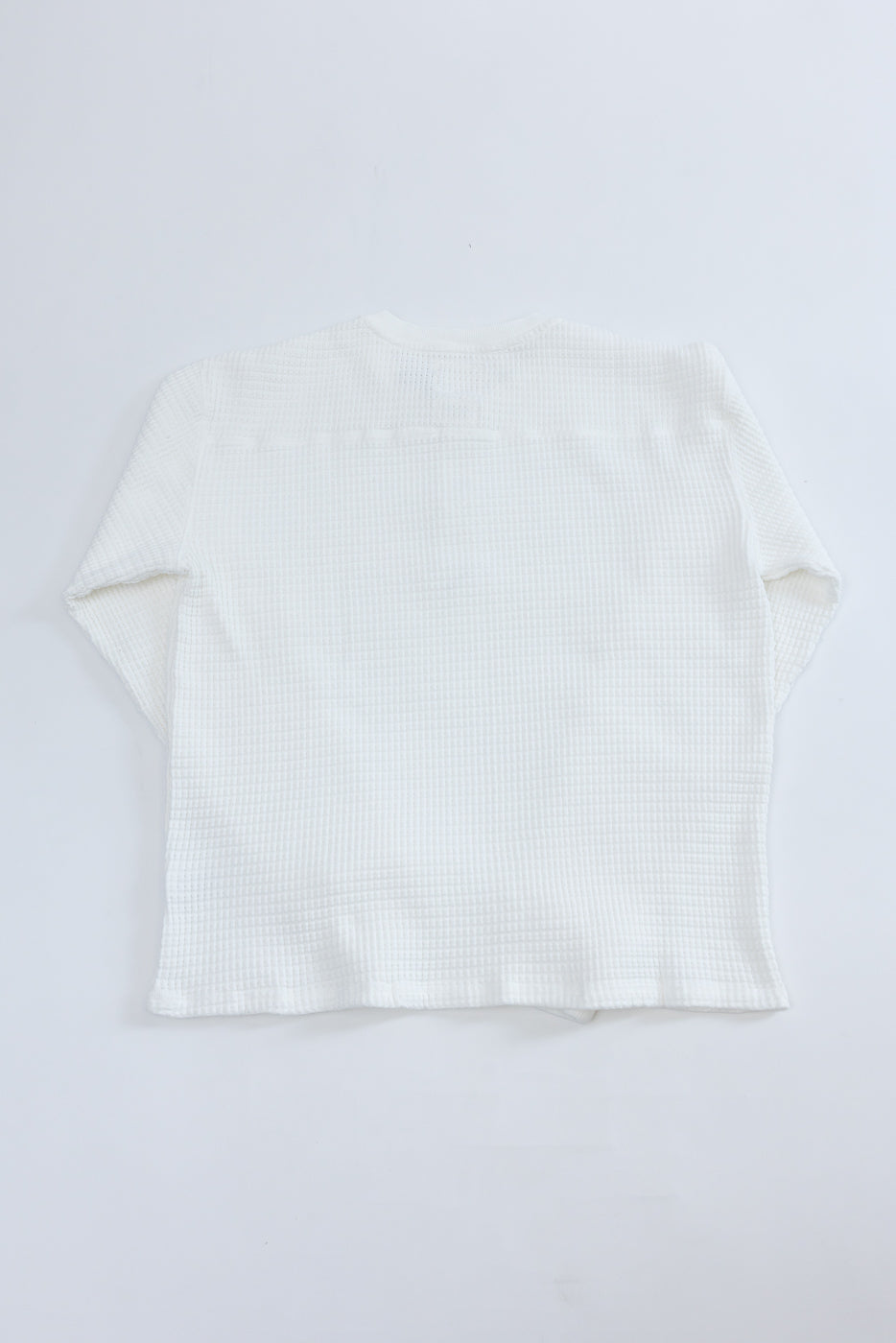 Flat lay back view of a white waffle-knit long-sleeve shirt.