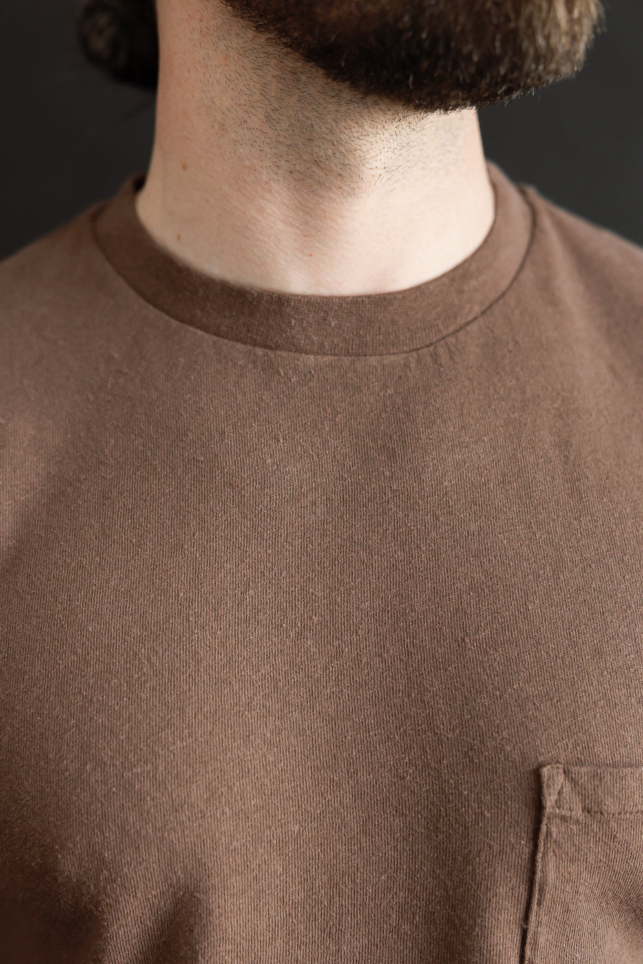 Close-up front view of Aztec brown cotton hemp T-shirt, male model, pocket detail visible.
