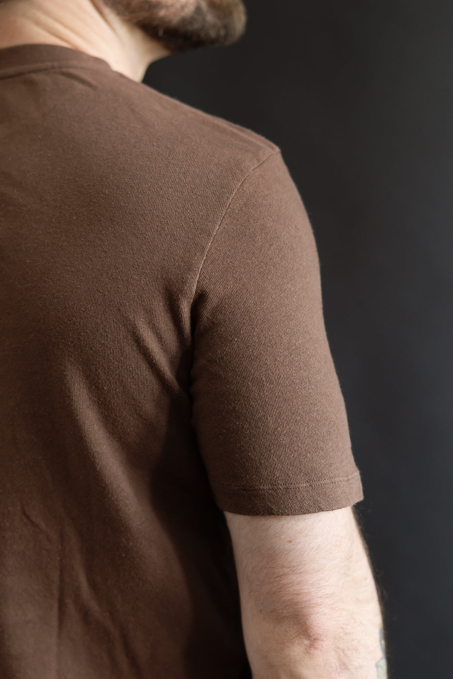Close-up of male model's upper back and sleeve in brown cotton hemp t-shirt, rear view.