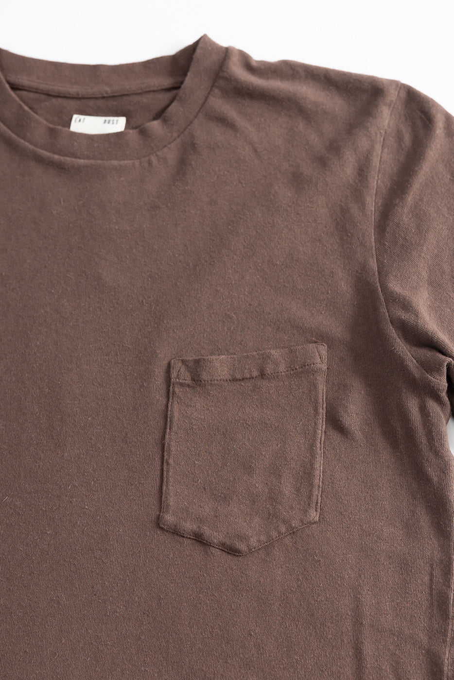 Close-up of front chest pocket and fabric texture on brown cotton hemp t-shirt.