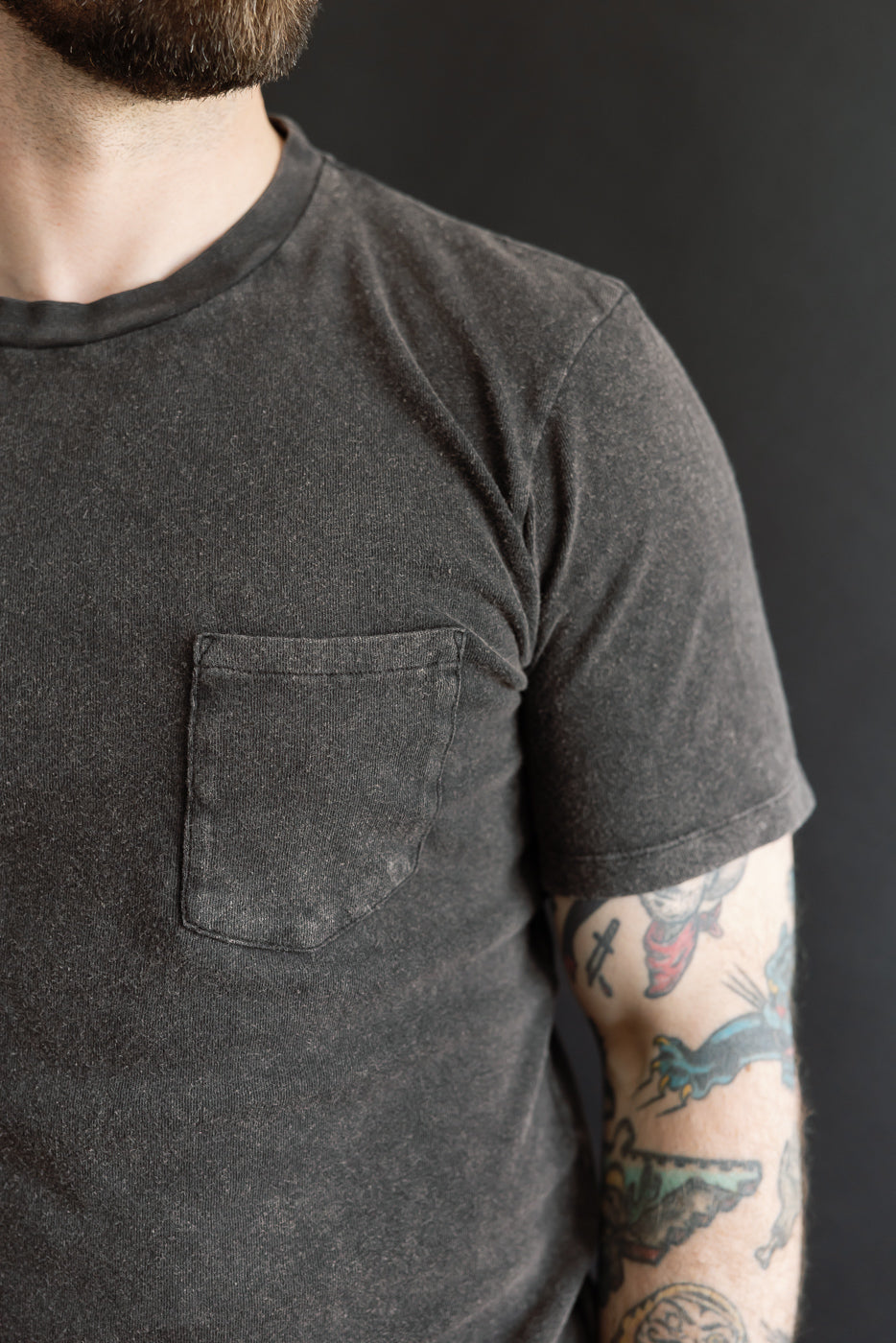 Close-up of front left side of vintage black cotton hemp pocket t-shirt on male model, 5'9