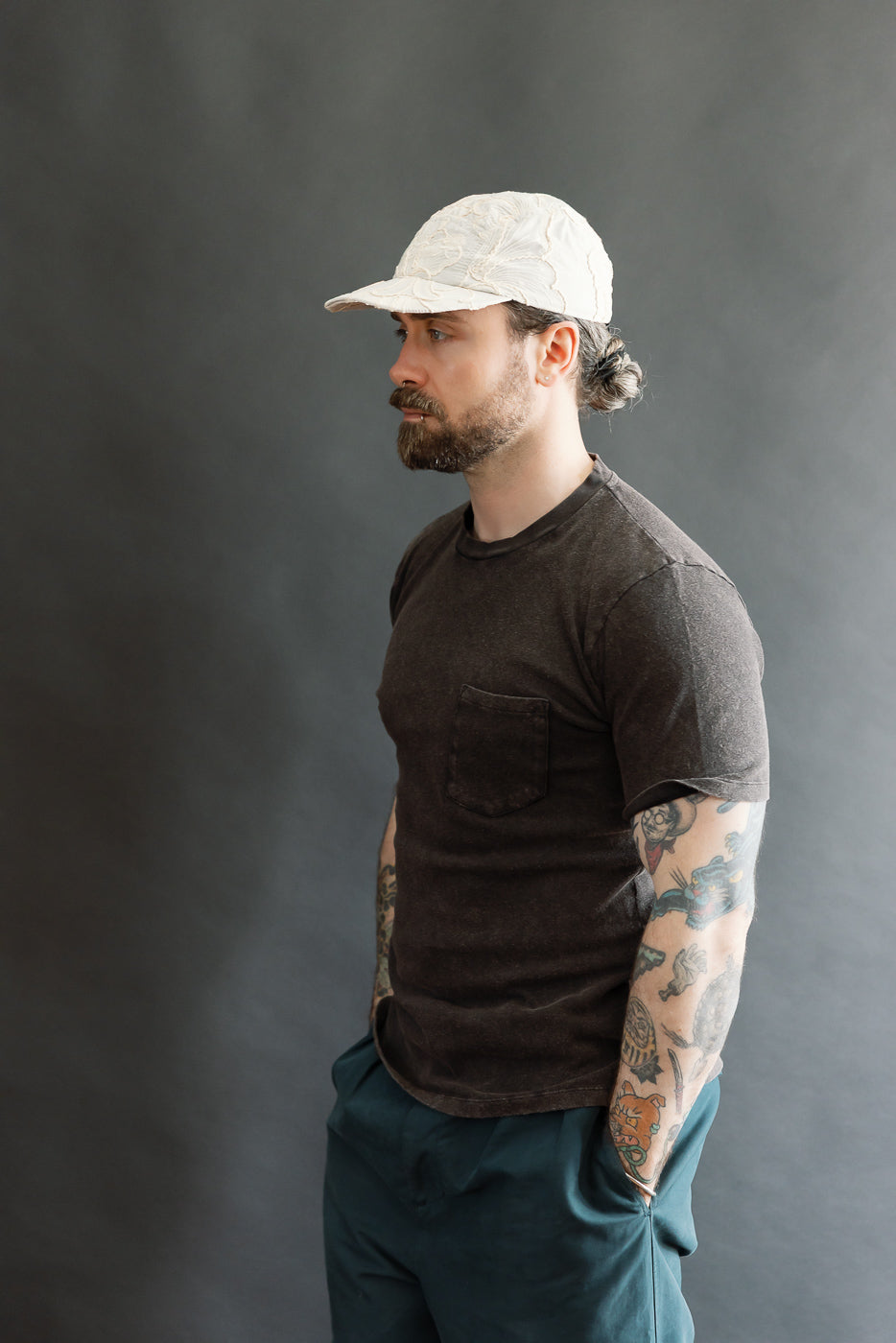 Male model 5'9, 165lbs athletic build, side view, wearing vintage black pocket T-shirt, close-up showing left side and chest pocket detail.