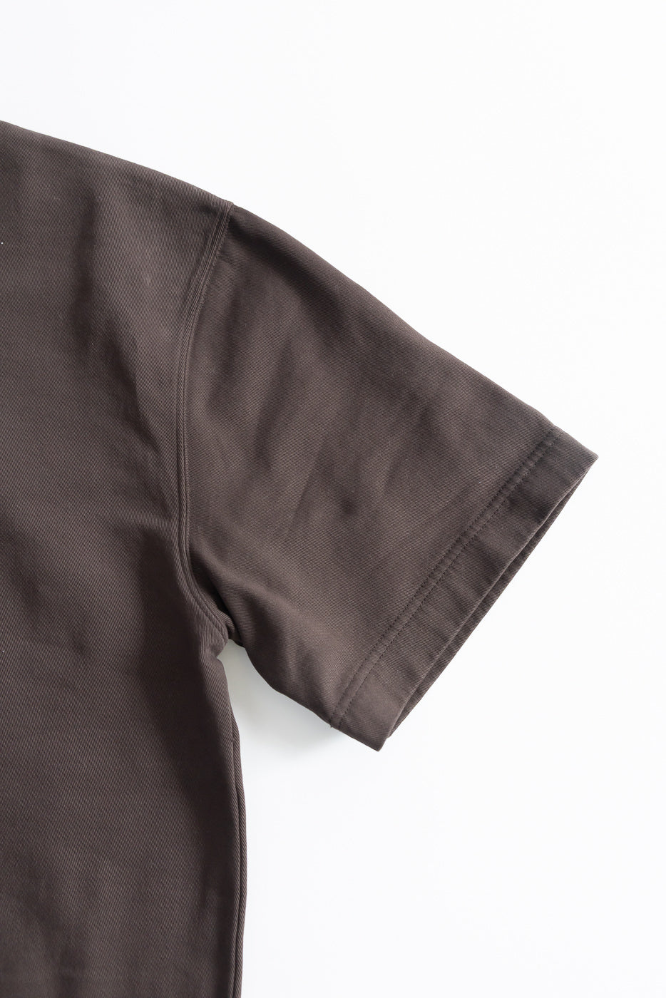 Close-up of right sleeve and shoulder, front view of brown twill short-sleeve T-shirt.