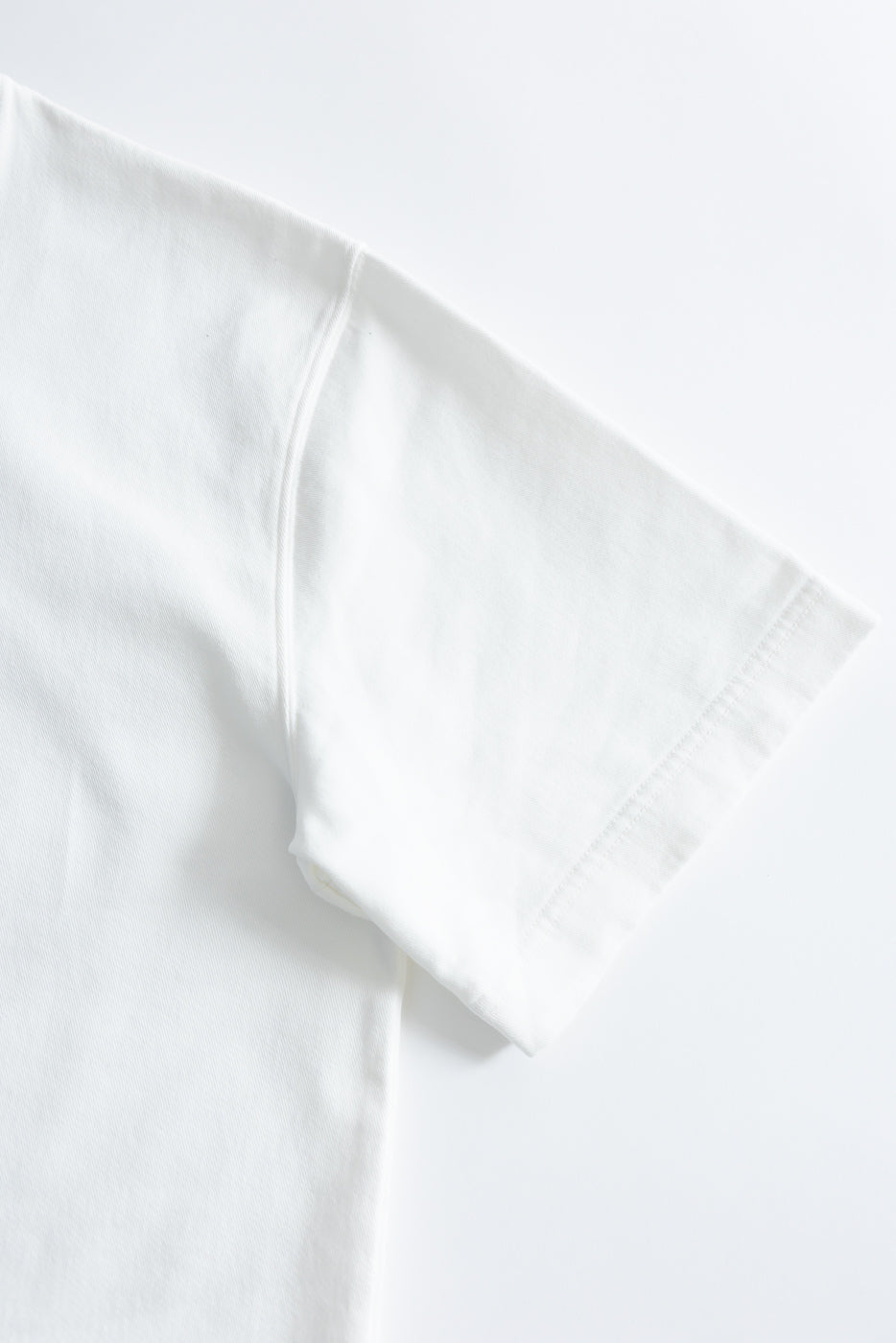 Close-up of M-J-009 - Power T Twill Jersey - Milk, showcasing the sturdy stitching on the sleeve hem and shoulder seam, highlighting the premium fabric quality and craftsmanship synonymous with Dant's offerings.