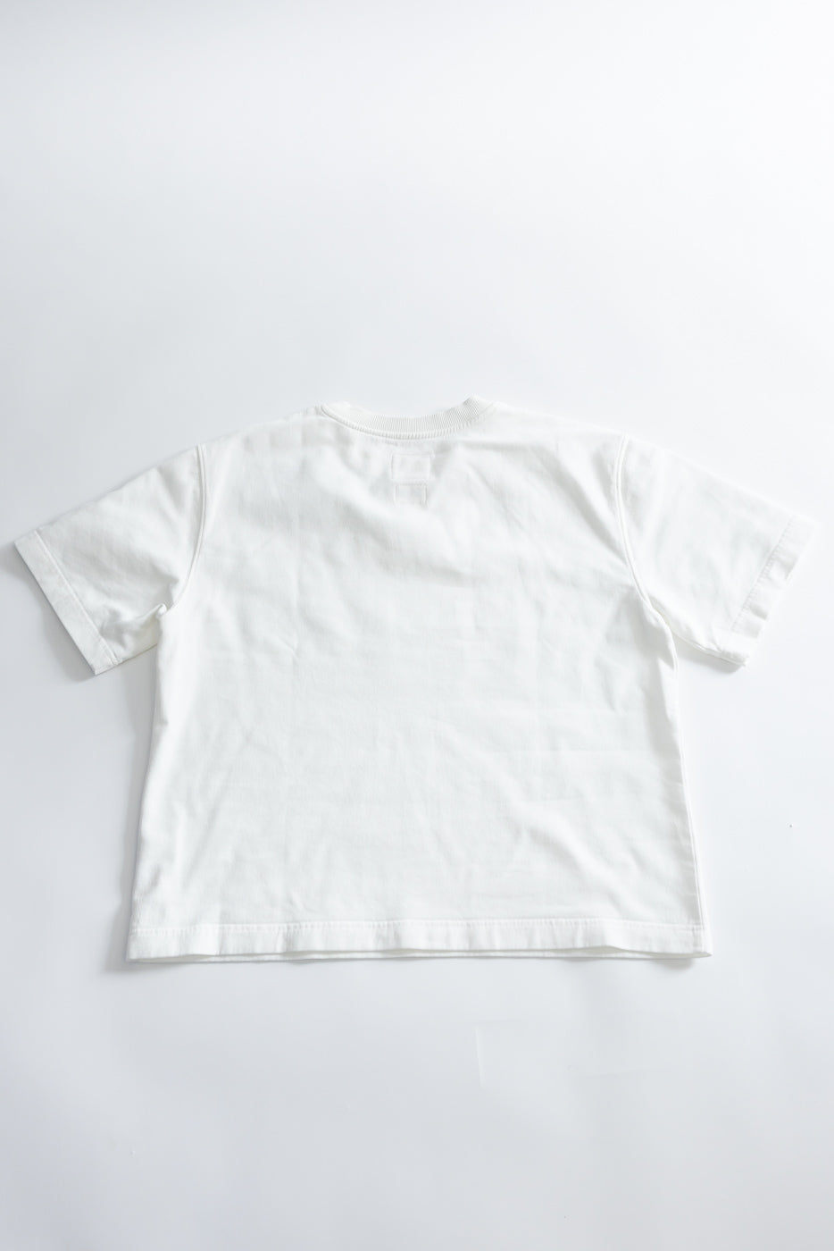 M-J-009 - Power T Twill Jersey - Milk: A back-facing, boxy-cut, white short-sleeved T-shirt with drop shoulders and a thick ribbed collar, crafted from soft, durable cotton twill jersey, laid flat.