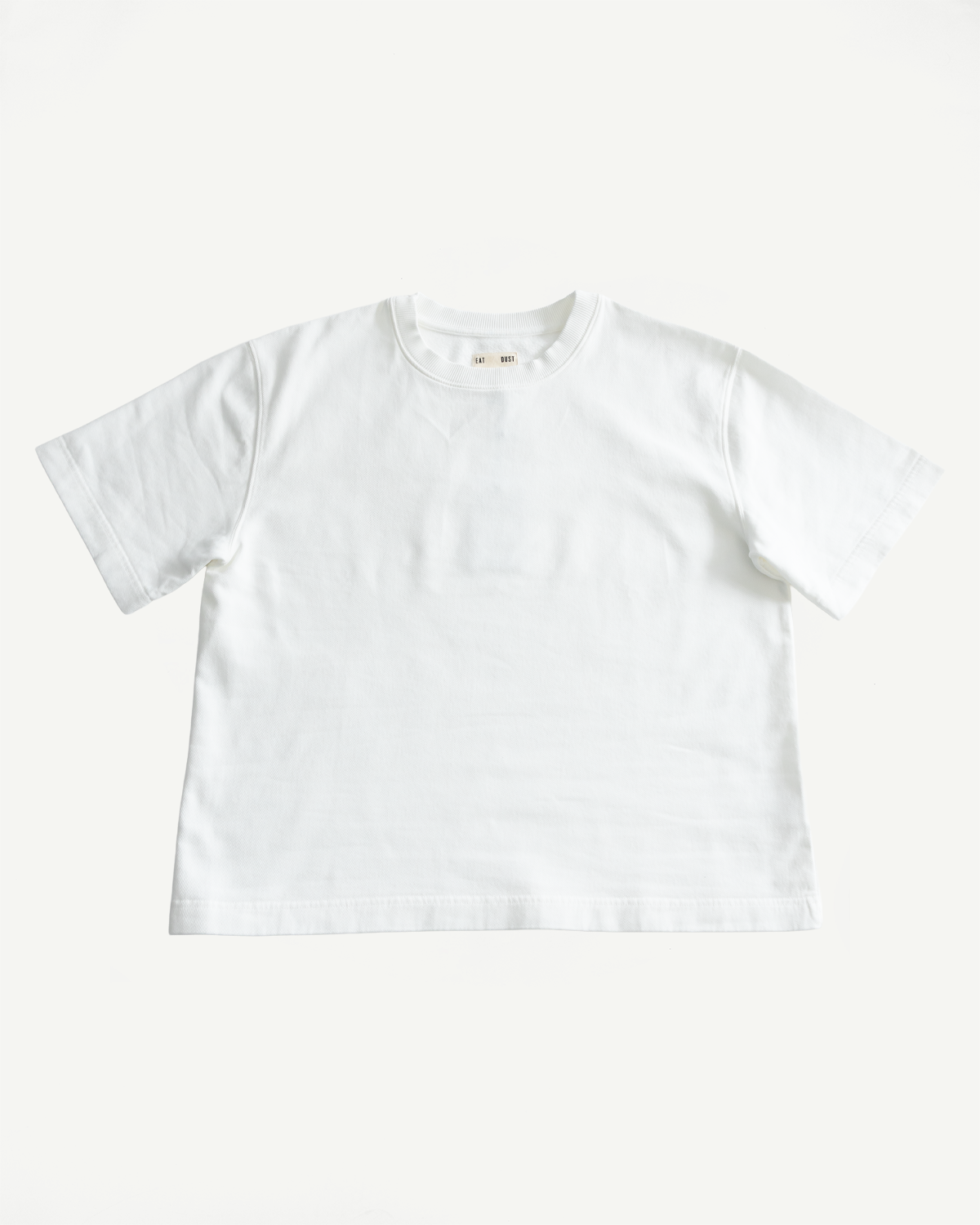 M-J-009 - Power T Twill Jersey - Milk: A plain white, short-sleeved crew-neck T-shirt with a boxy fit and thick ribbed collar, crafted from soft cotton twill jersey, laid flat on a white background.