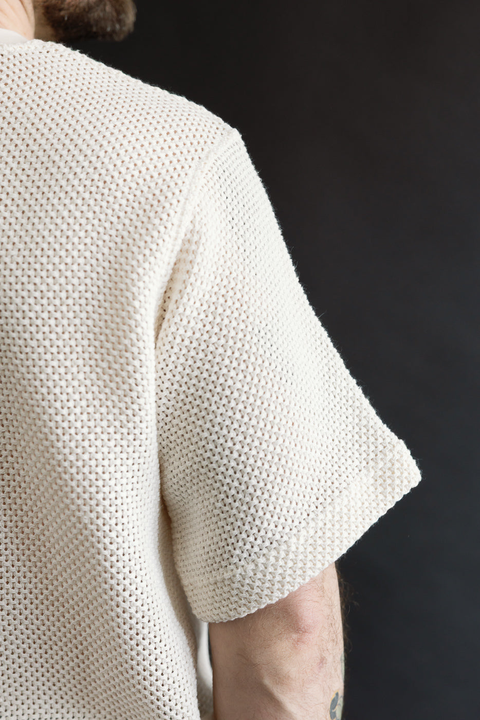Close-up of male model’s right sleeve and shoulder, ecru cotton knit t-shirt, textured weave