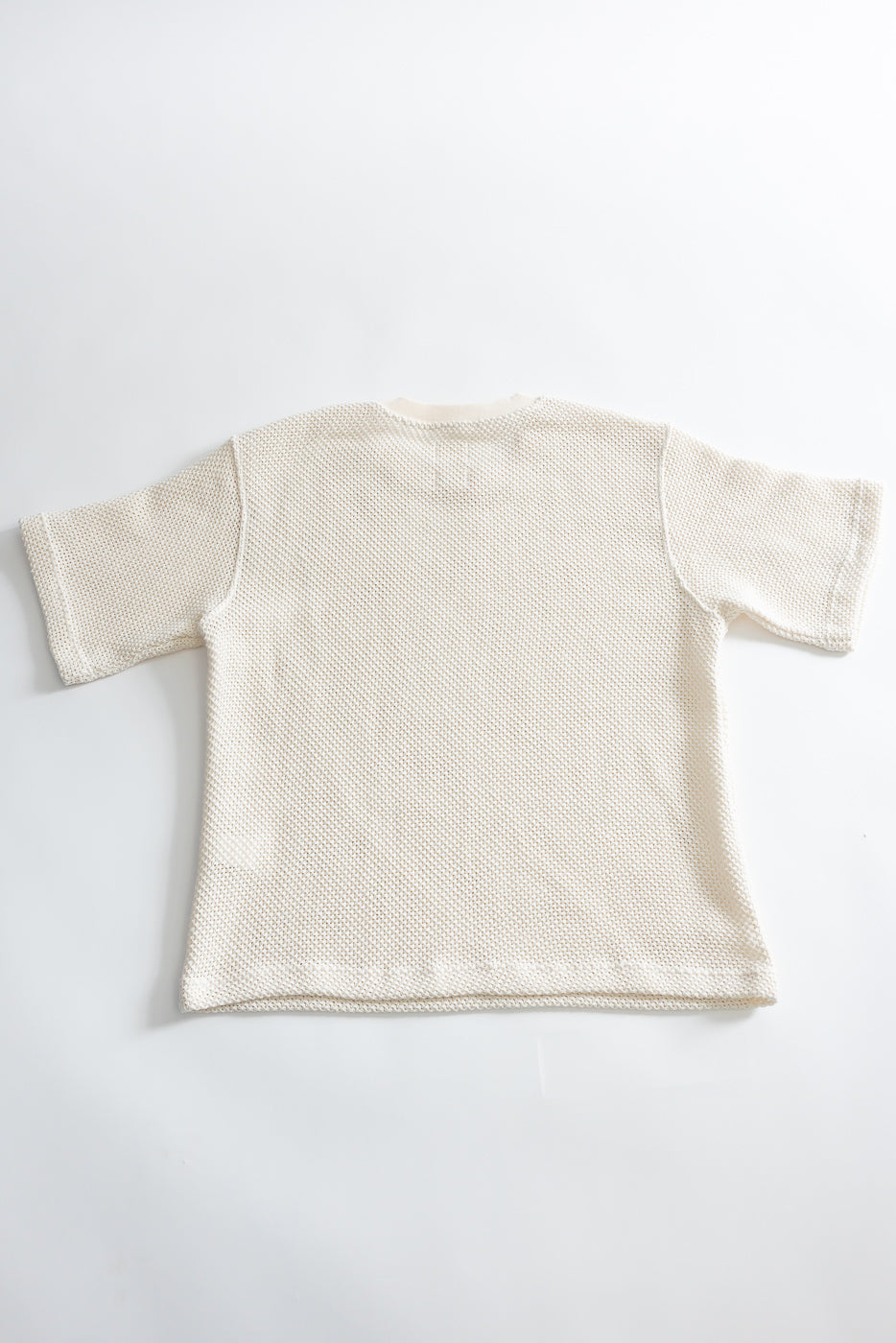 Flat lay of back side of ecru short sleeve cotton textured T-shirt, showing fabric detail.