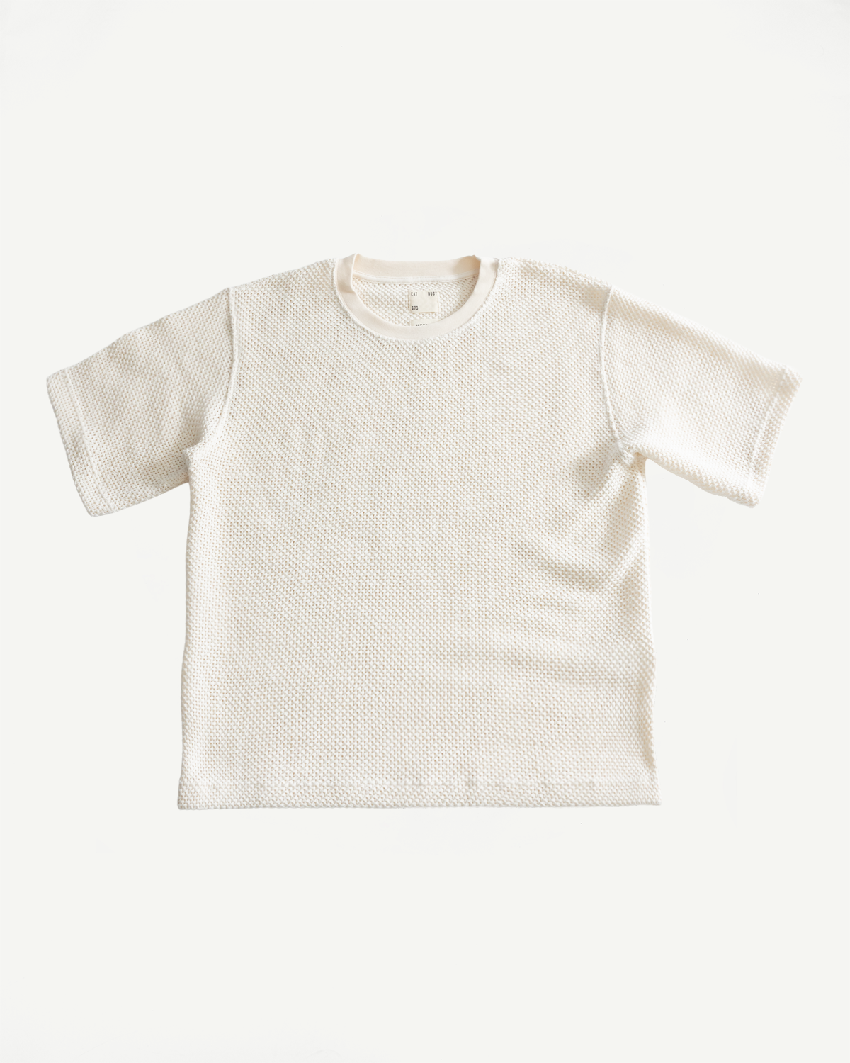 Flat lay of ecru cotton short sleeve t-shirt, front view showing textured fabric and crew neck.