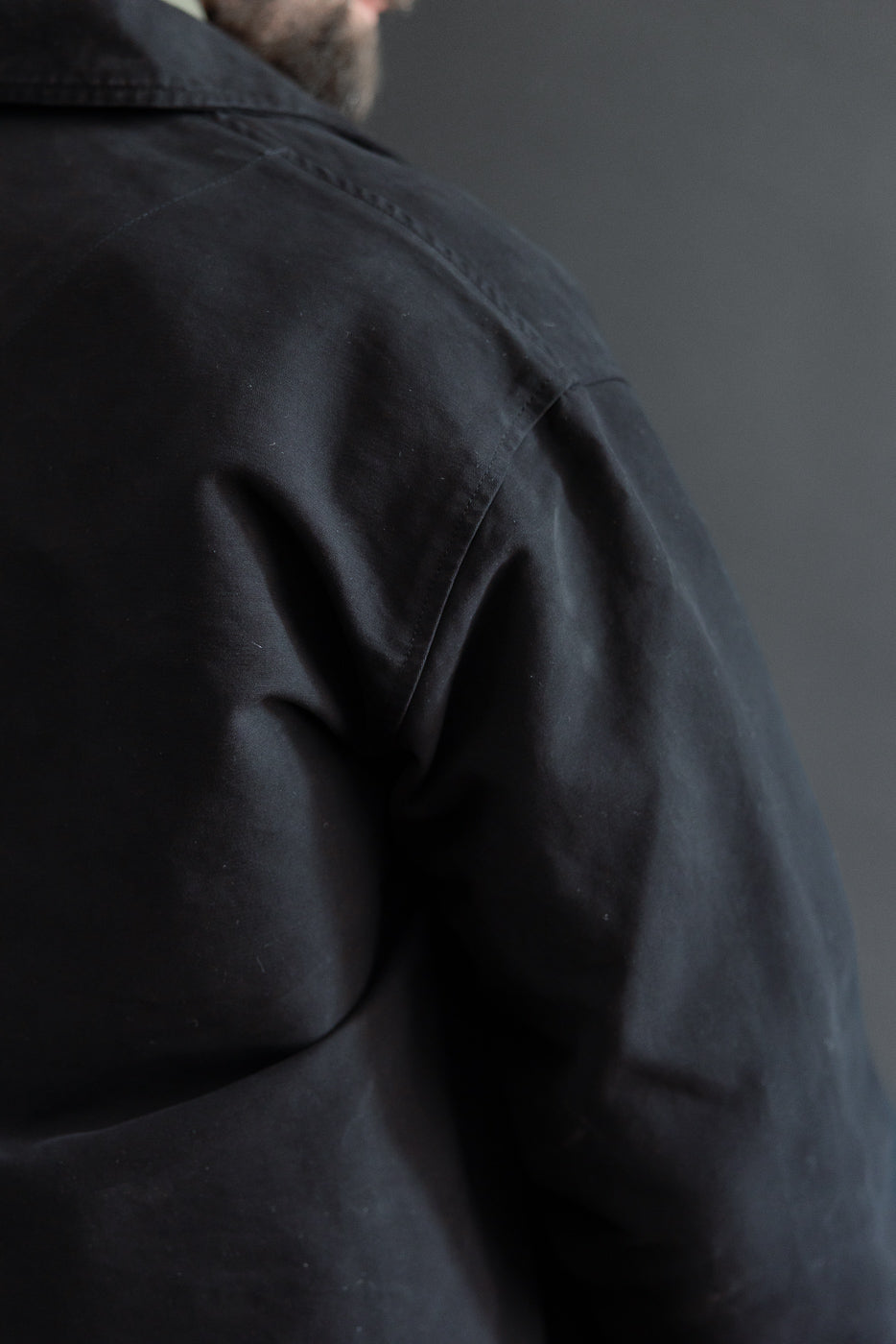 Close-up back view of a black jacket on a male model, 5'9
