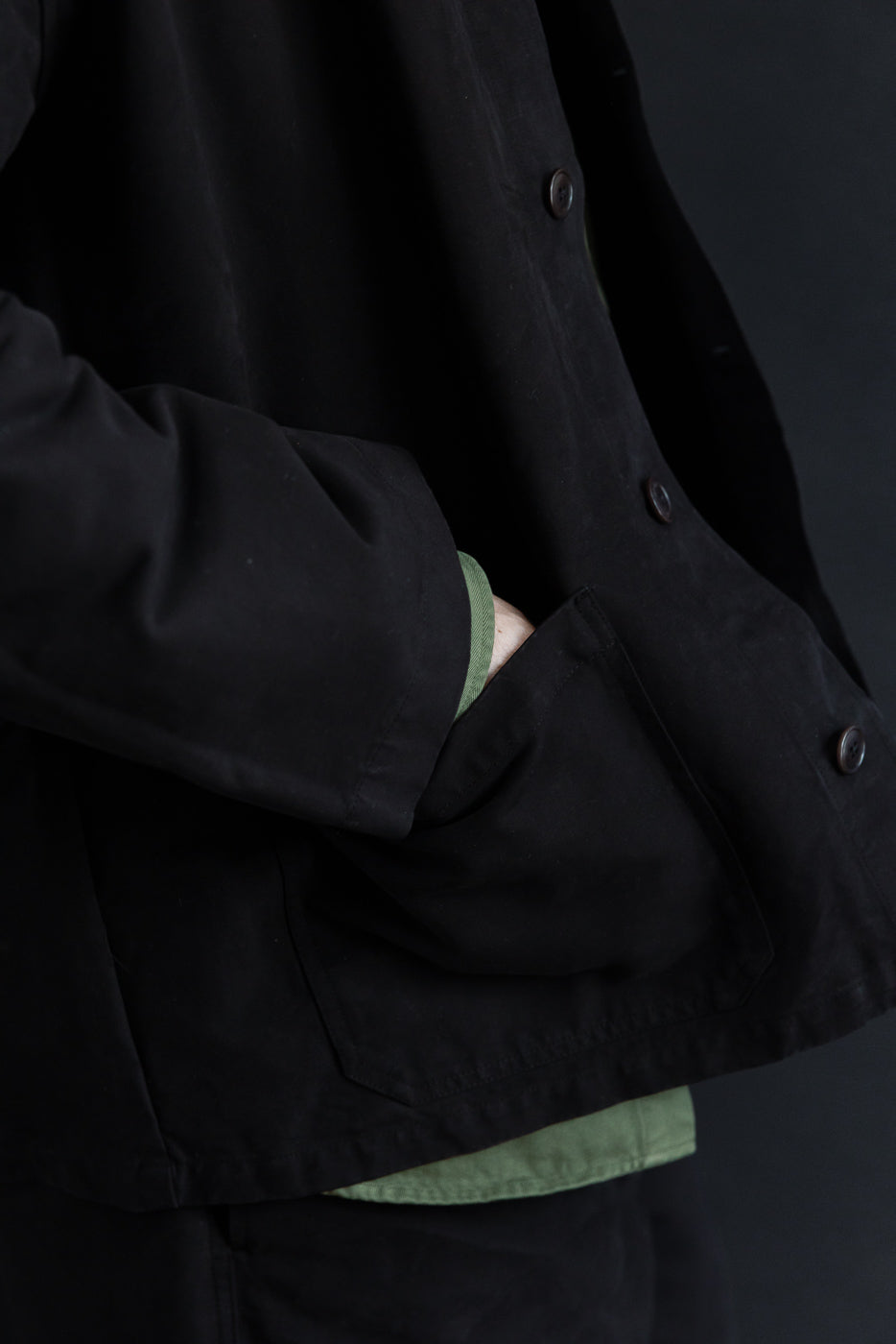 Close-up side view of a black jacket pocket and fabric texture on a male model.