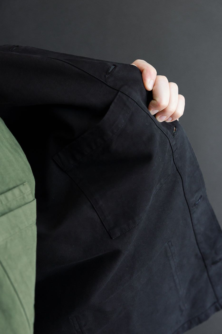 Close-up of the back side of a black cotton jacket showing a large patch pocket.