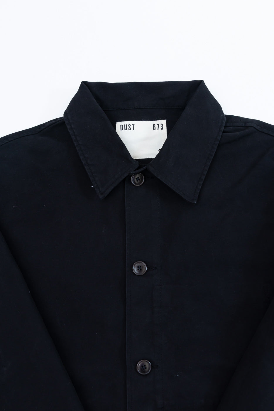 Front close-up of a black button-down shirt featuring a pointed collar and dark buttons.