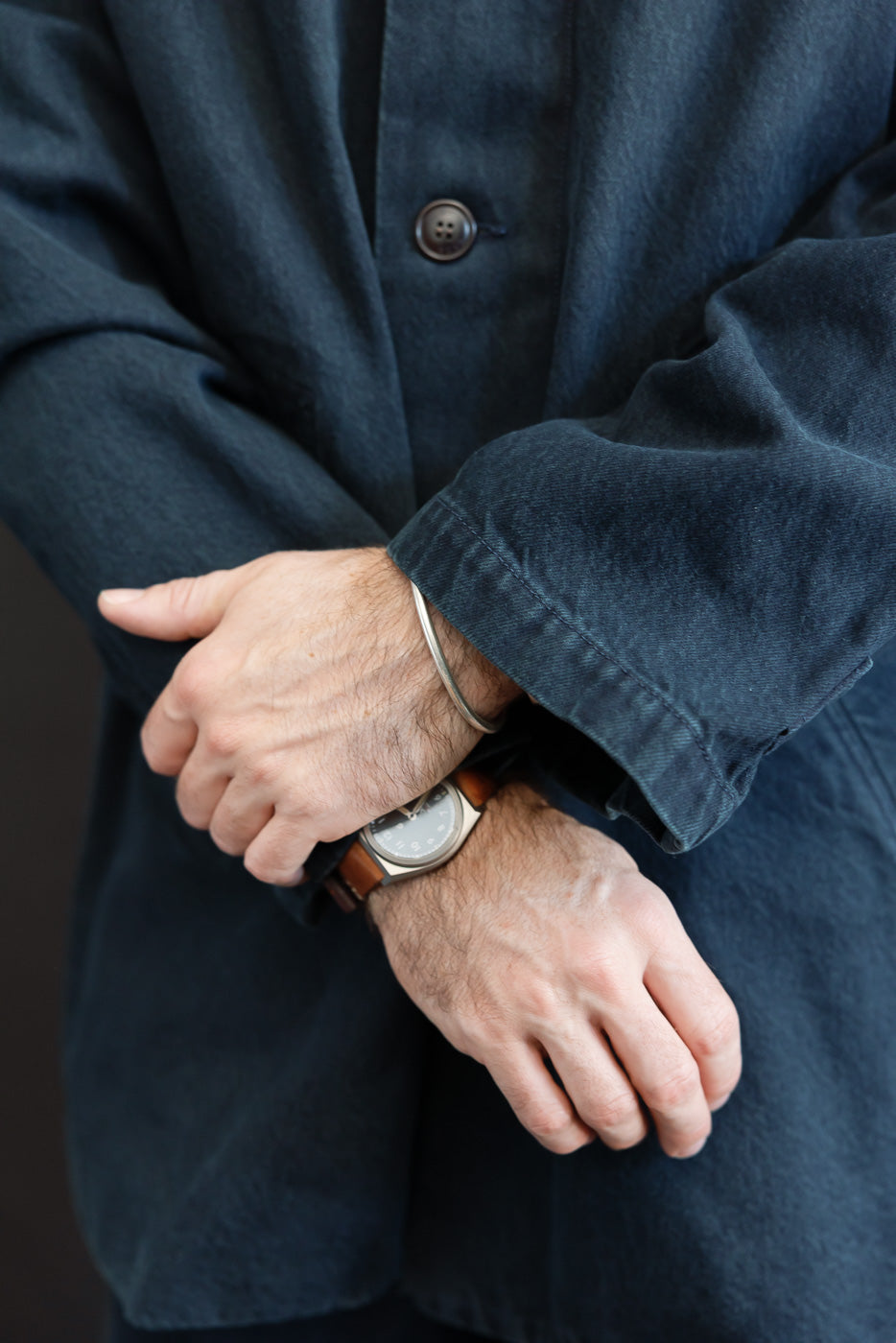 Close-up of the front left sleeve and button detail on a navy blue casual jacket.