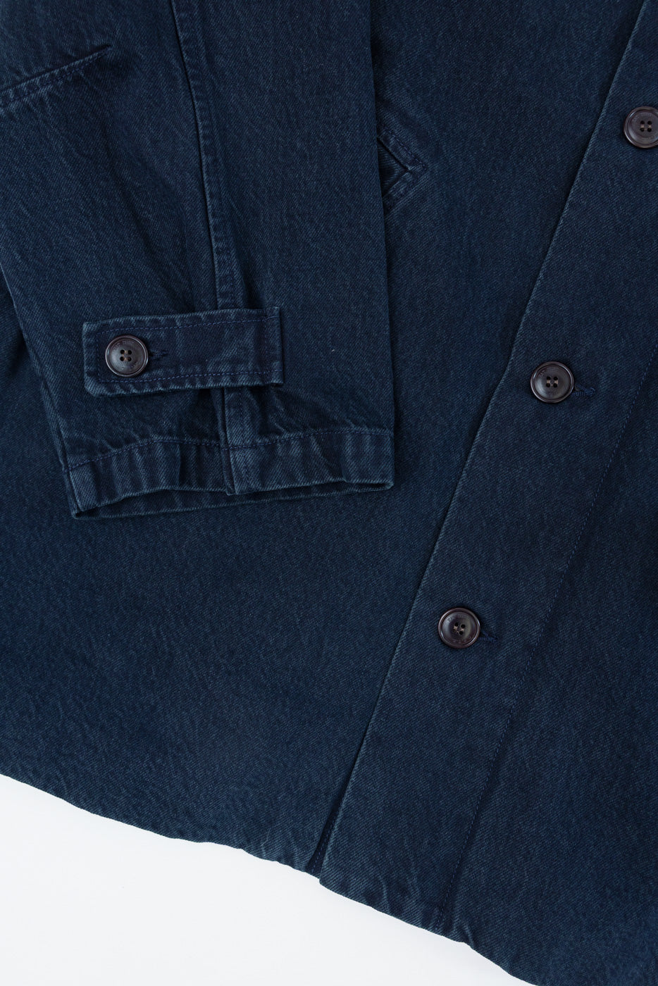 Close-up of the front cuff and button placket of a navy blue denim shirt showing fabric texture.