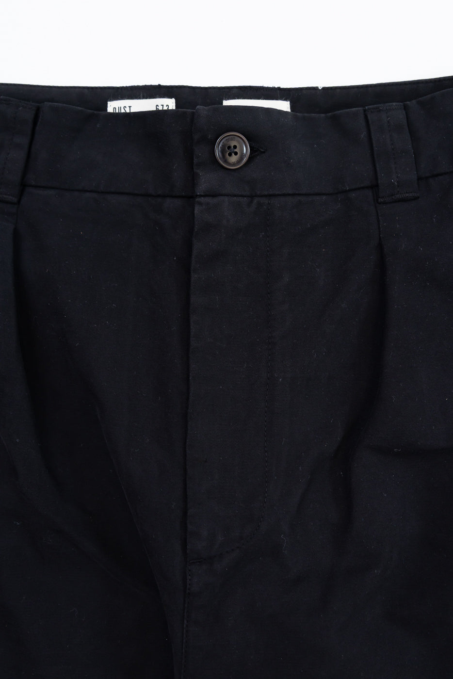 Close-up front view of black trousers showing the waistband, button closure, and fabric texture.