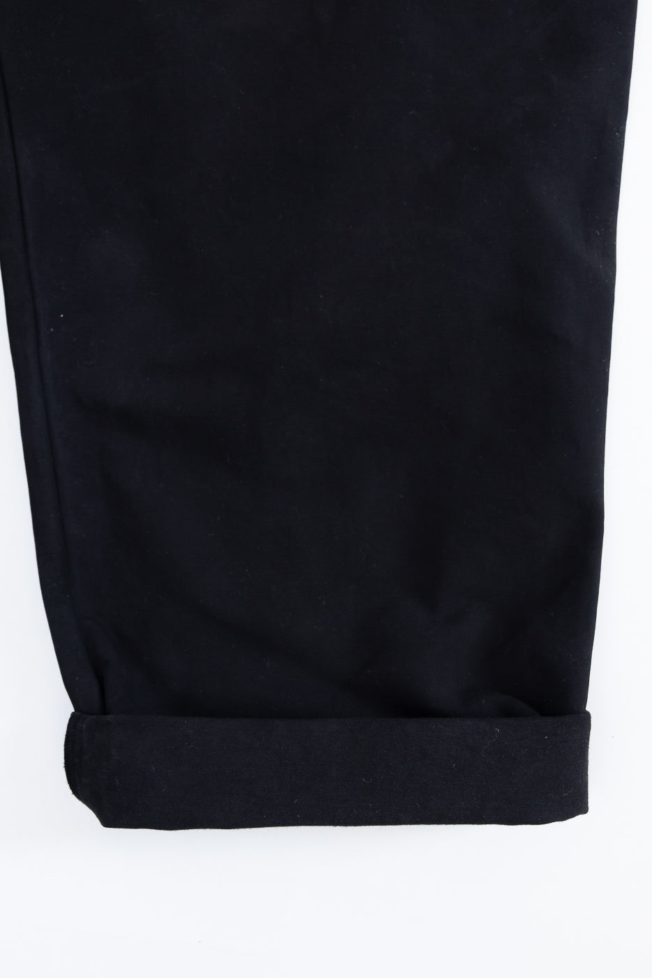 Close-up of the bottom hem of black pants showing the rolled-up cuff detail.