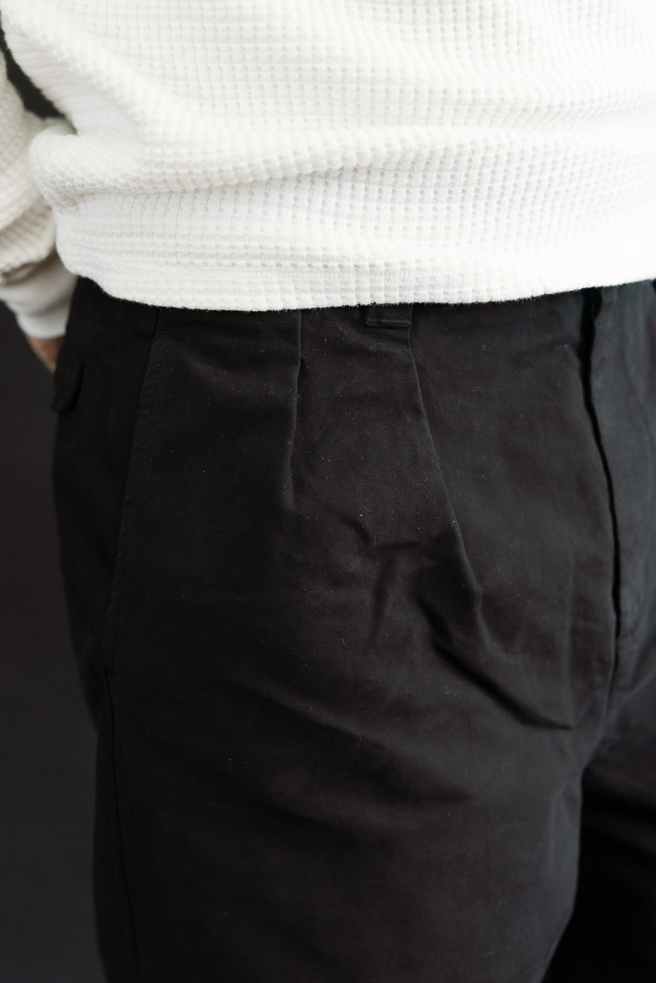 Close-up of the front right hip of black trousers on a male model, 5'9