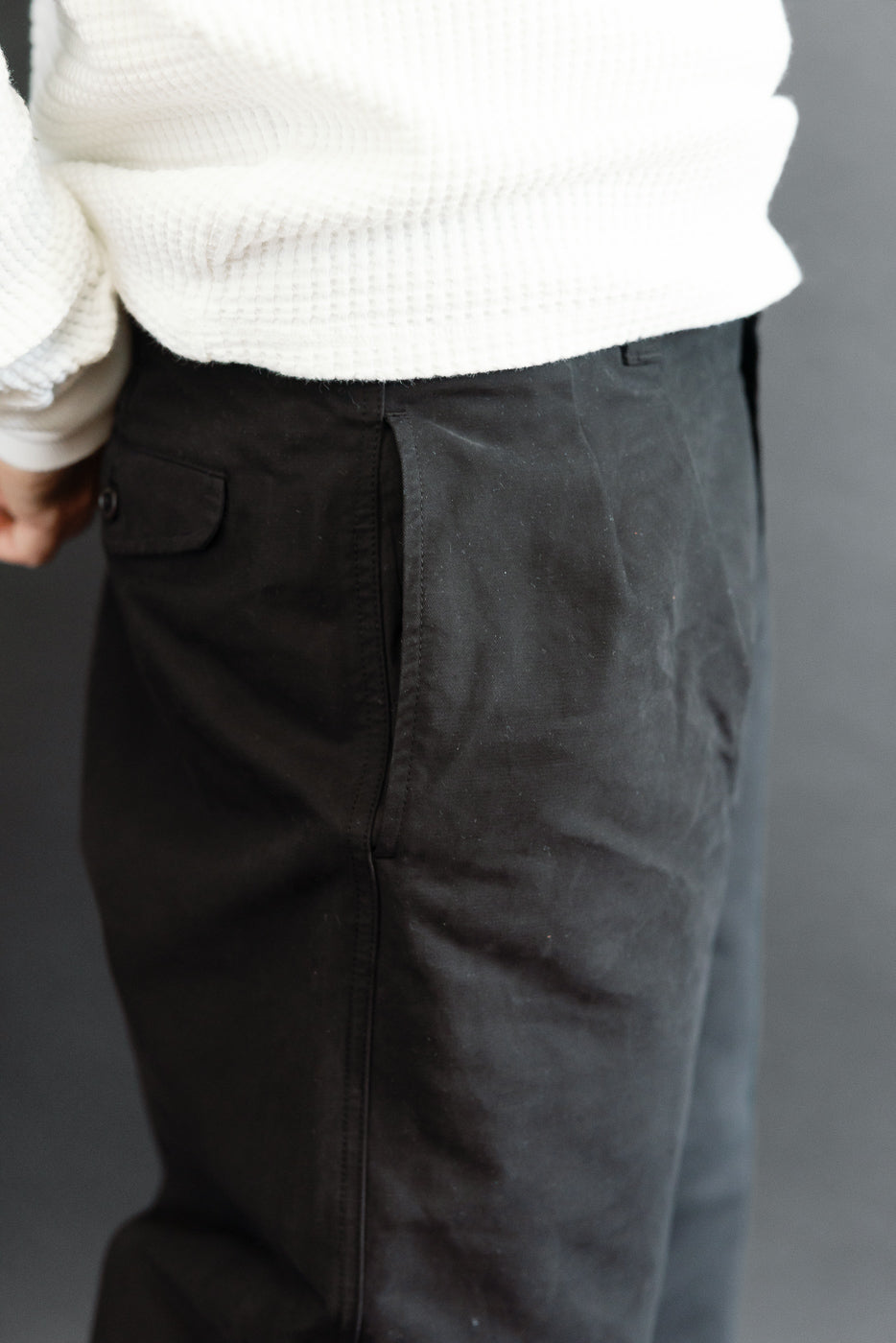 Close-up of the left hip and pocket of black trousers on a male model, 5'9