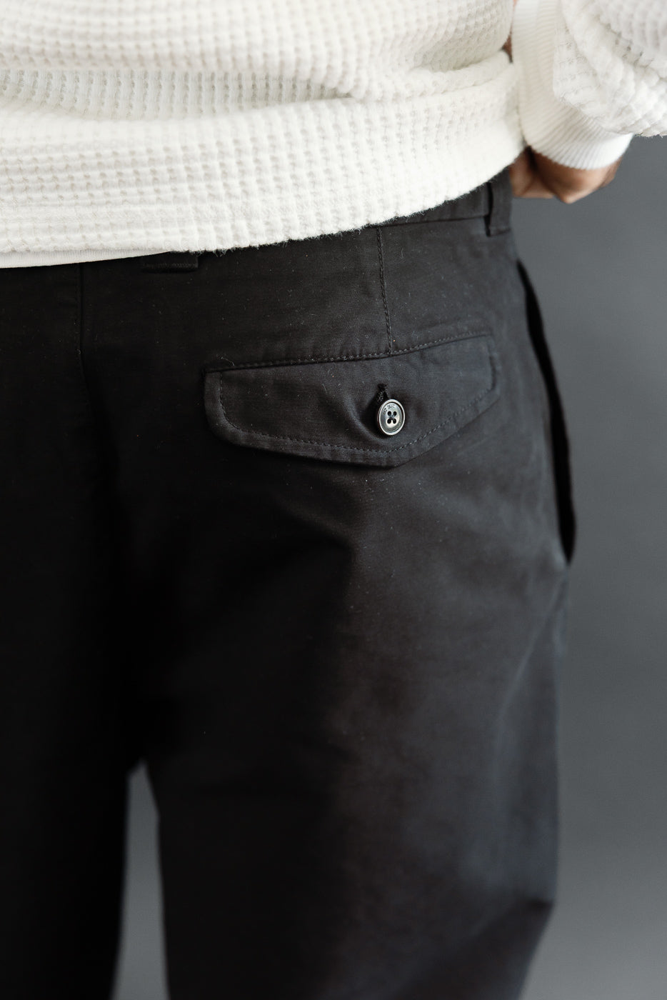 Close-up of the back right pocket on black trousers, worn by a 5'9