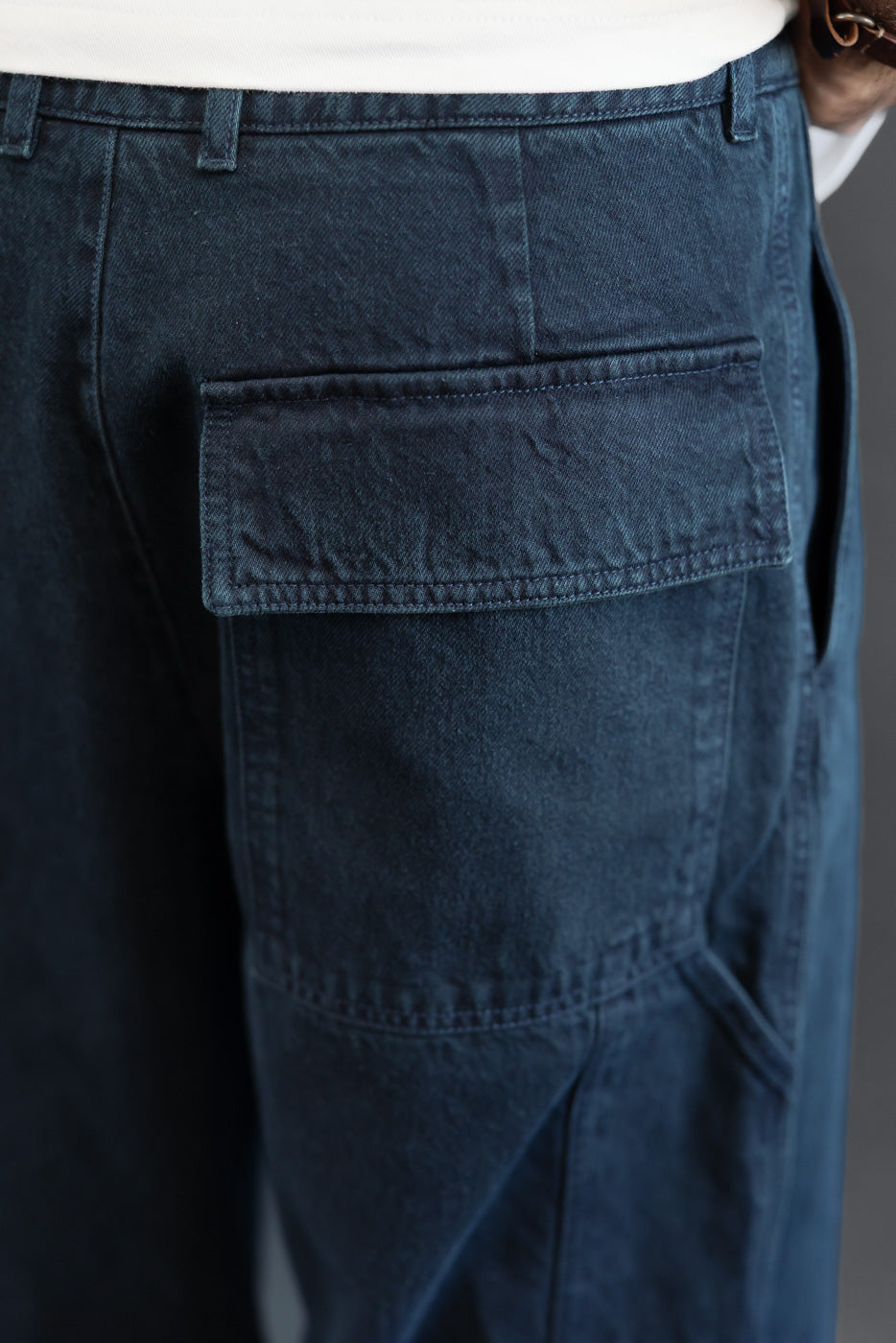 Close-up side view of a navy blue denim cargo pant pocket and fabric texture.