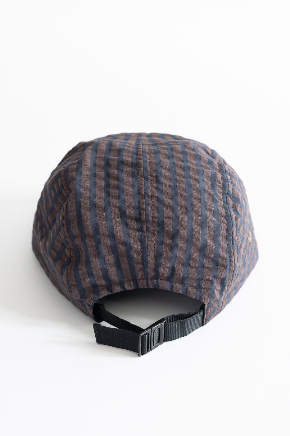 Close-up of back side of striped seersucker 5-panel cap with black adjustable strap