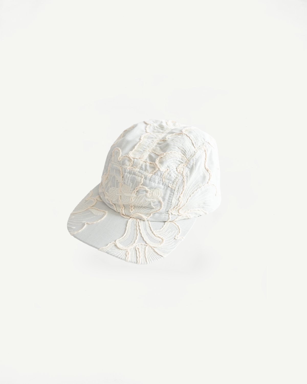 Flat lay front view of wheat-colored embroidered cotton 5-panel cap, showing brim and crown details.