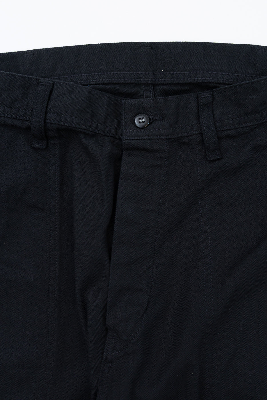 Close-up front view of black chino pants waistband, button closure, and herringbone texture