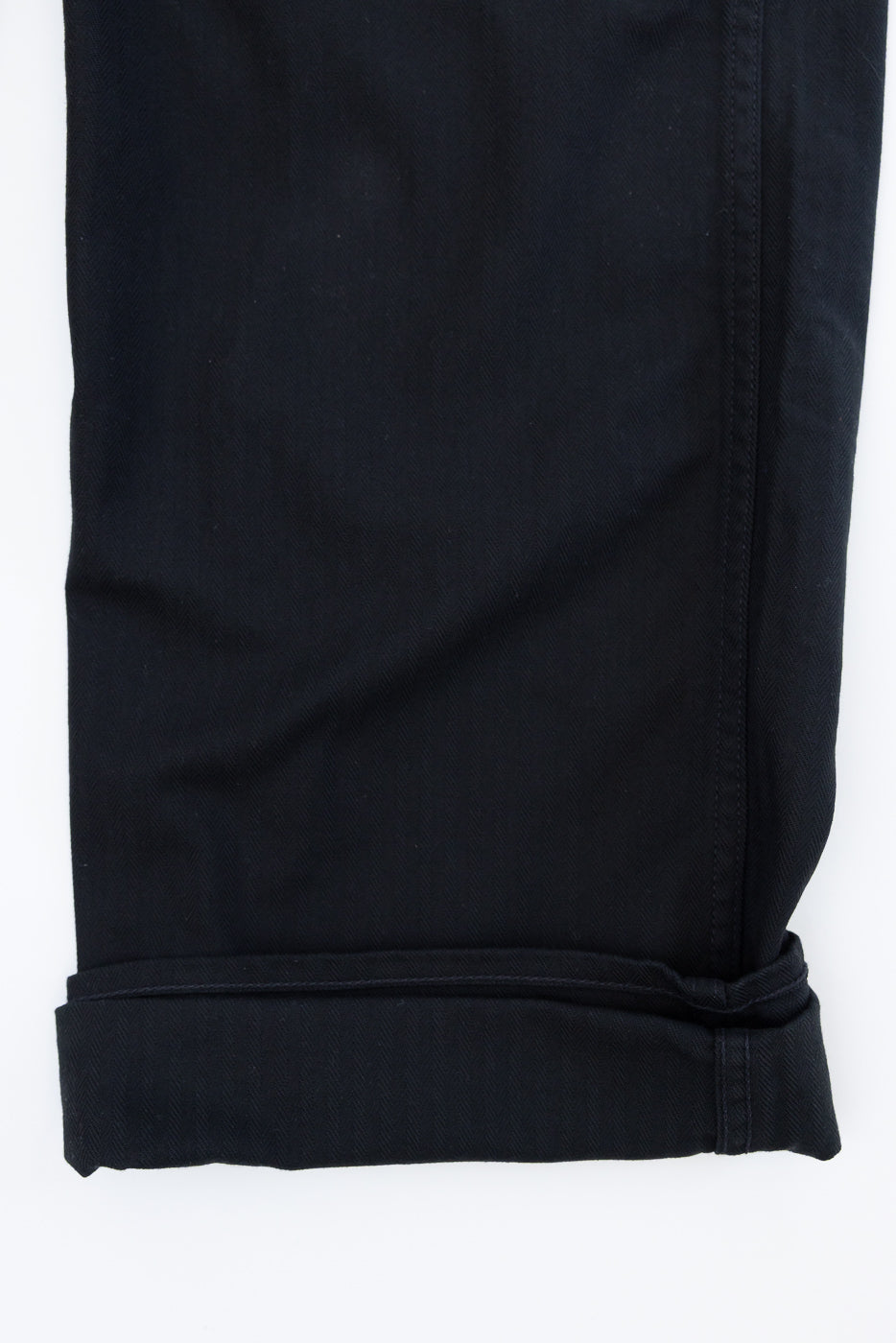 Close-up of black selvedge pants hem, showcasing rolled cuff and fabric texture, front view